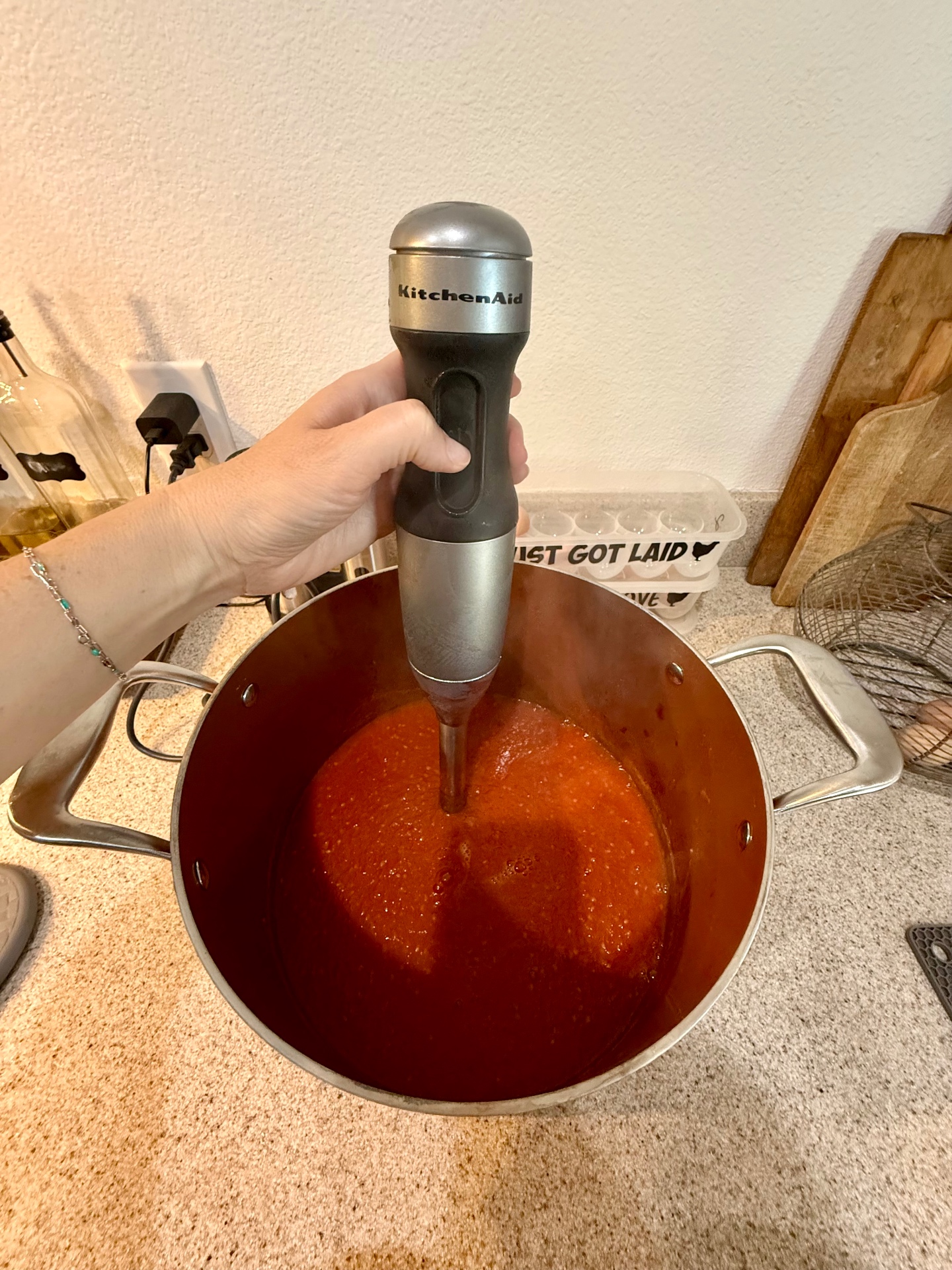 KitchenAid immersion blender blending homemade tomato sauce directly in a large stockpot.