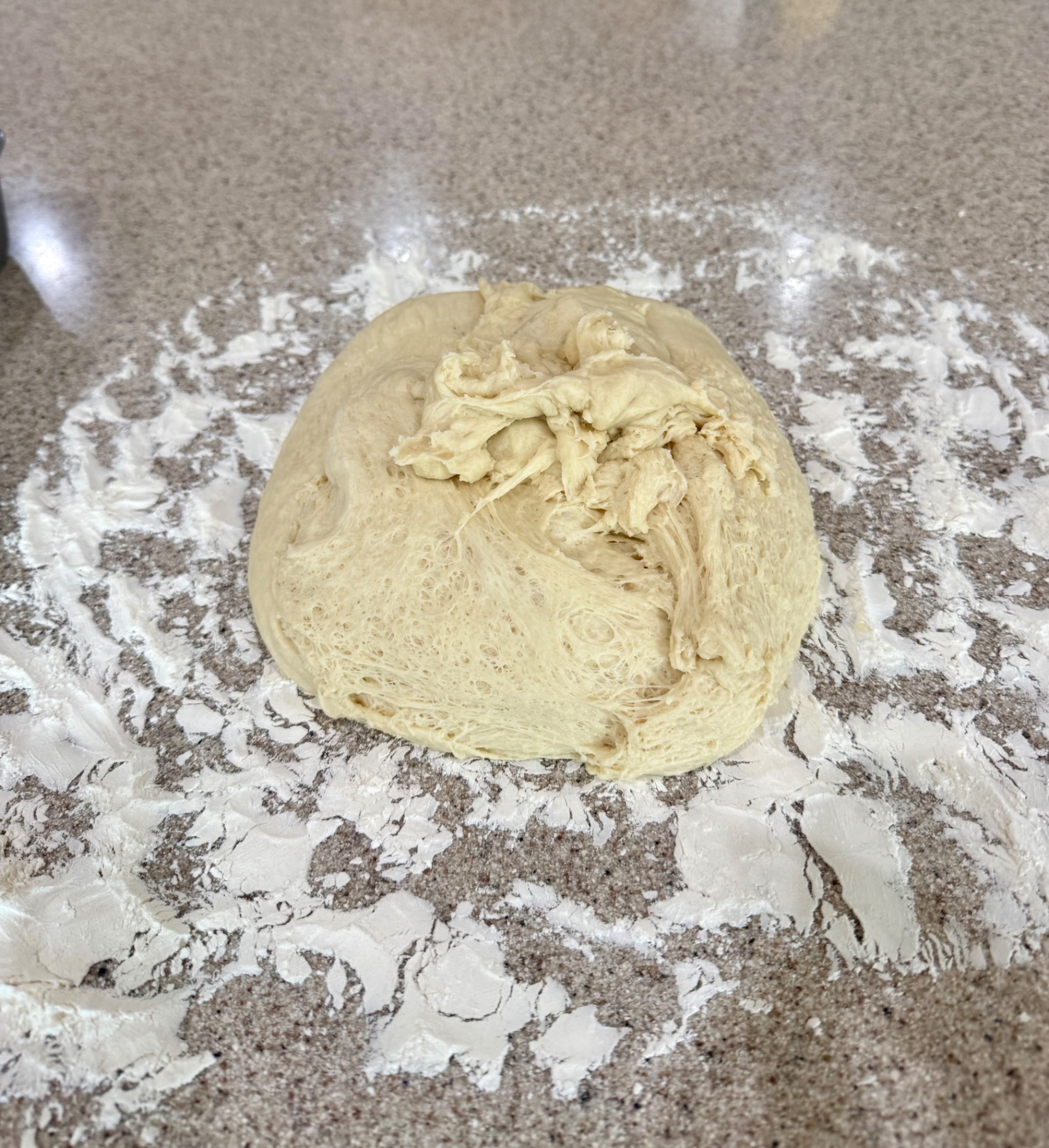 Soft bread machine dough turned out onto a lightly floured kitchen counter.