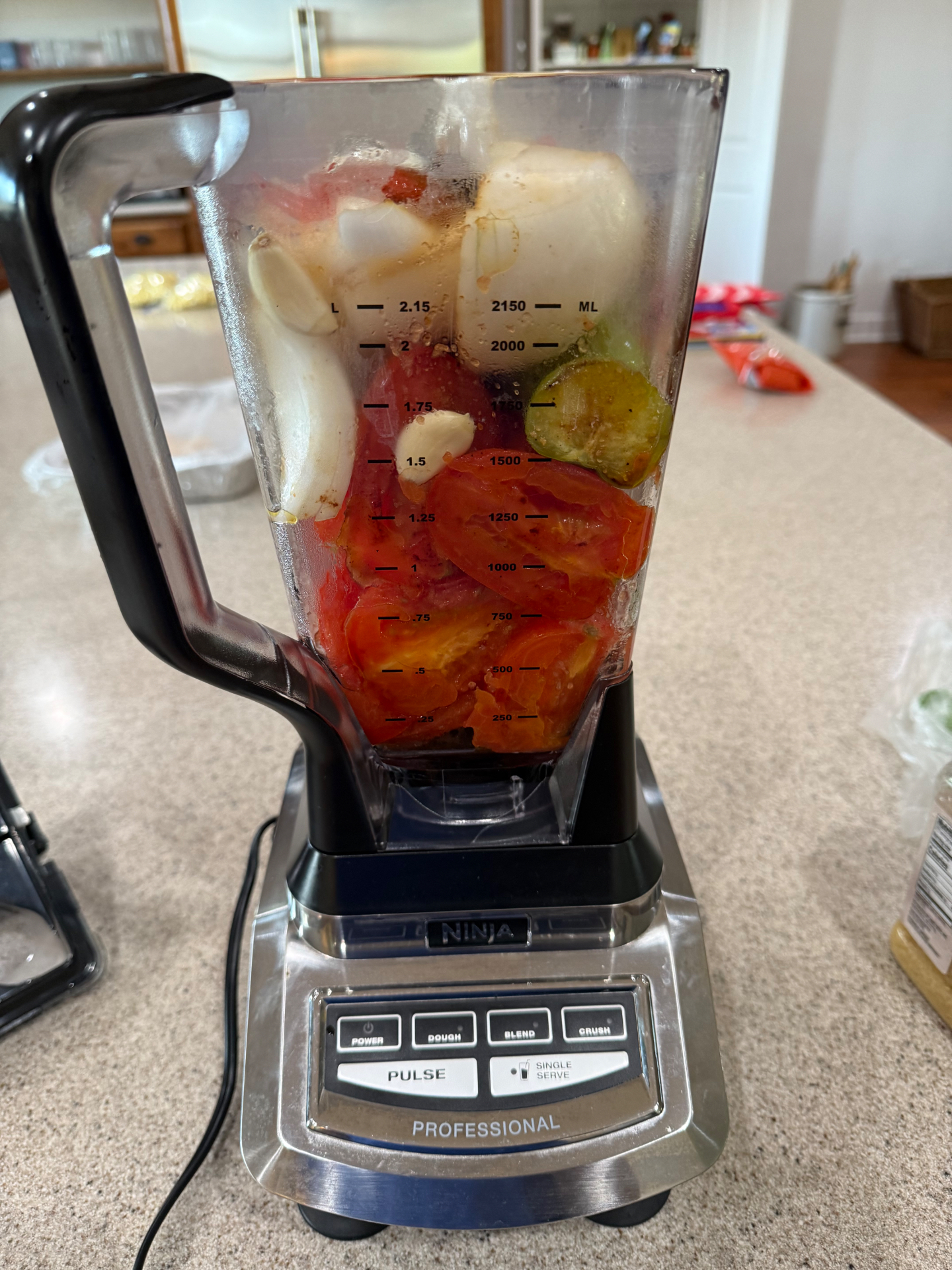 Ninja Professional blender filled with tomatoes, onion, garlic, and vegetables during food prep