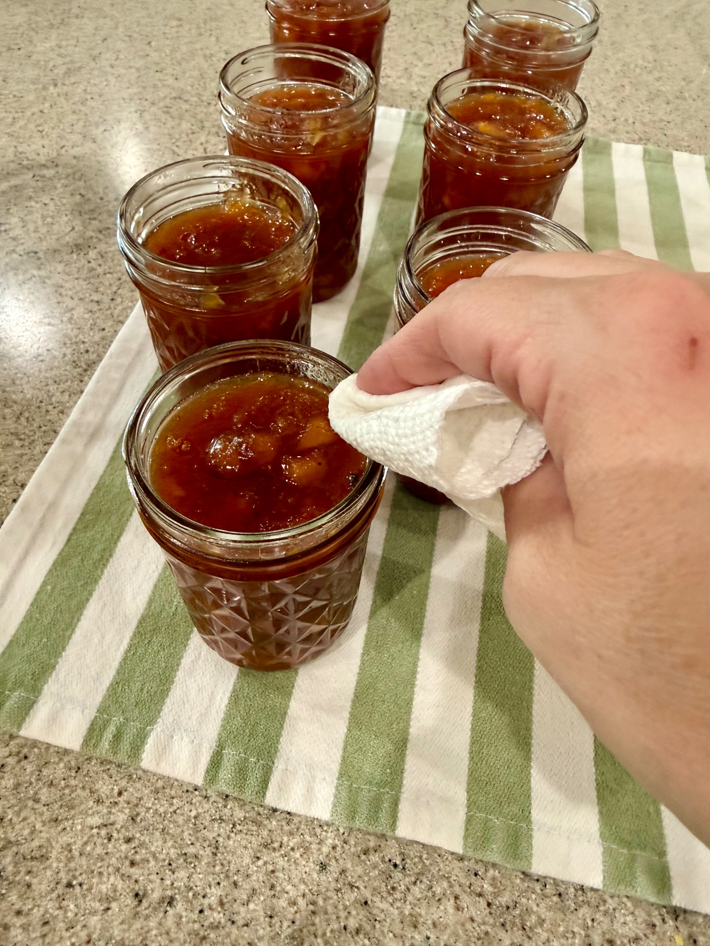 Wiping the rim of a filled canning jar with white vinegar before adding the lid.