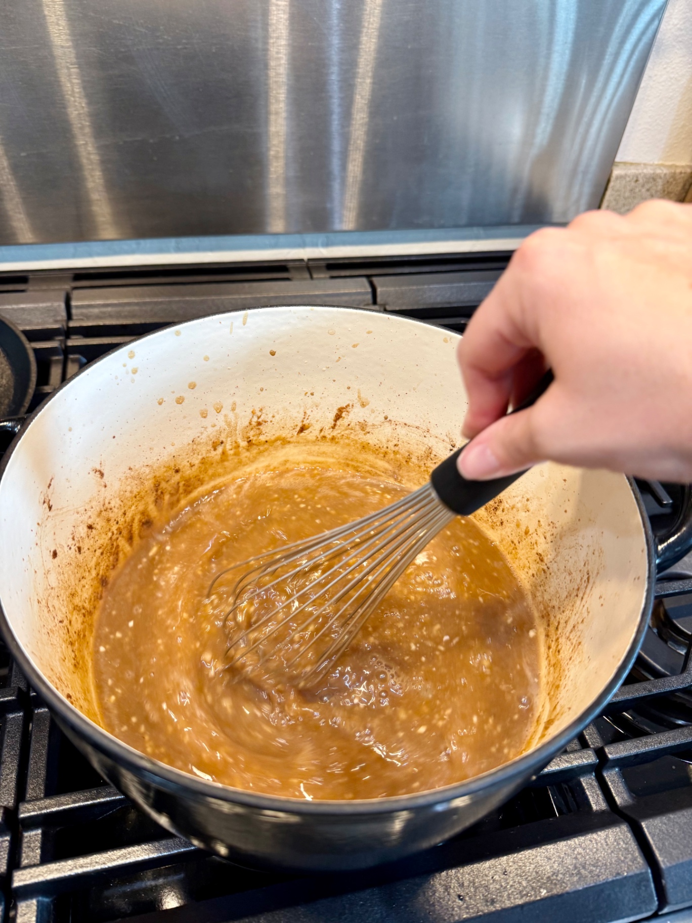 Whisking homemade beef gravy in the Dutch oven on the stovetop.