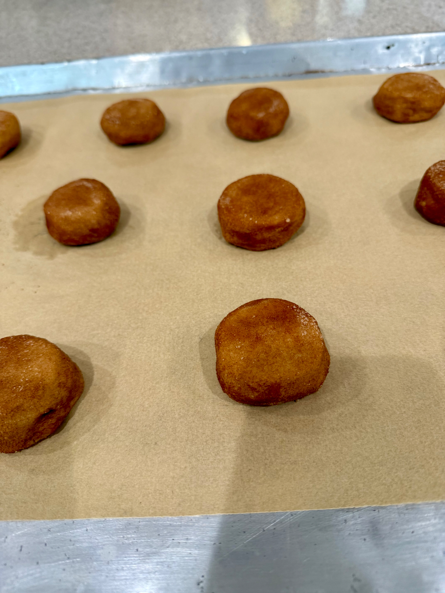 Cinnamon-sugar coated dough gently flattened into thick disks on a parchment-lined baking sheet.