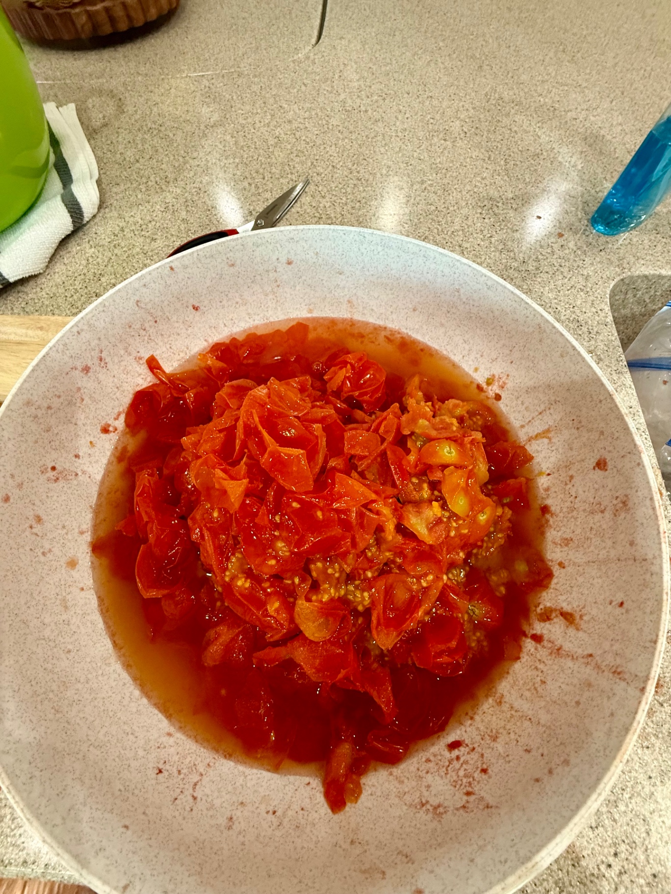 Peeled thawed garden tomatoes and tomato juice collected in a bowl.
