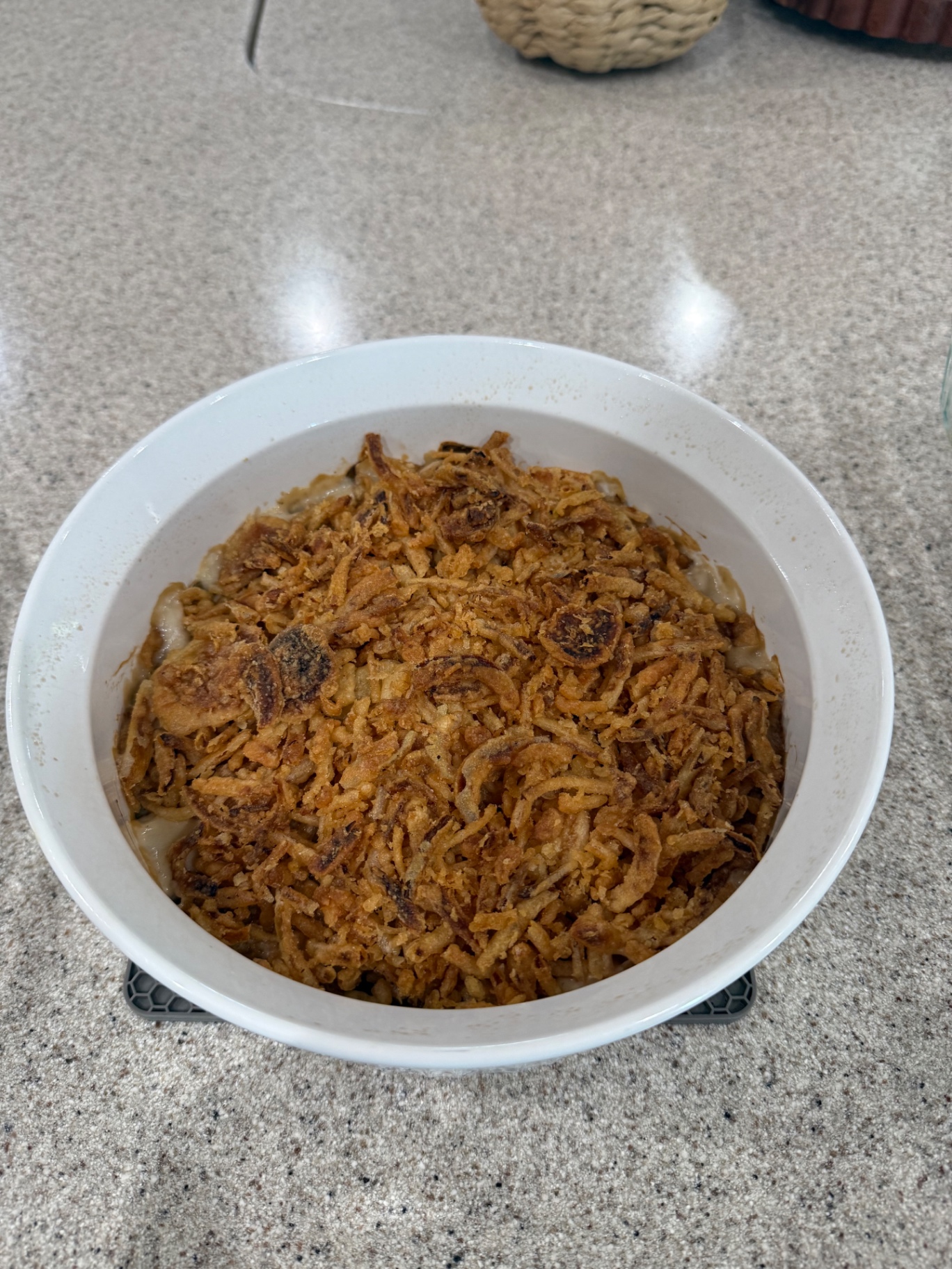 Finished baked green bean casserole with golden brown fried onions in a white baking dish.
