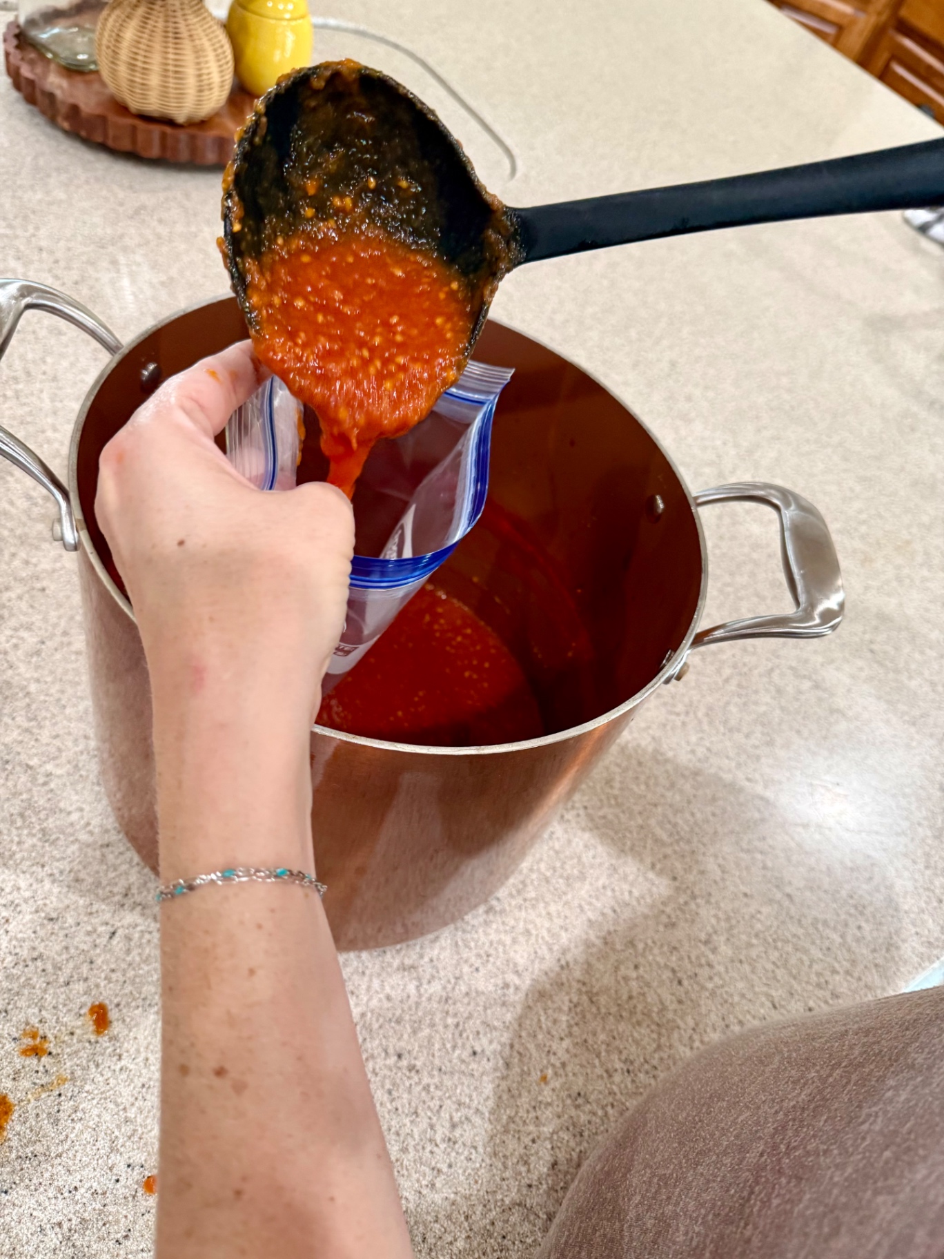 Ladling homemade tomato sauce into a quart freezer bag for storage.