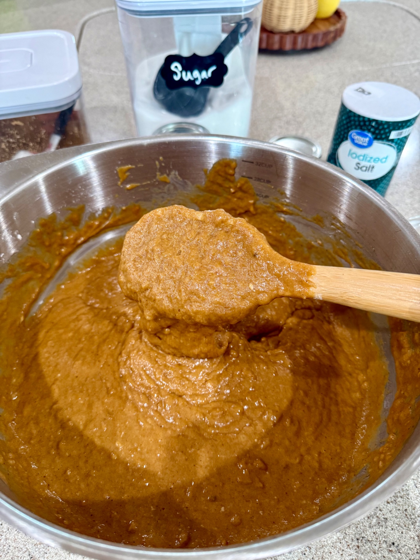 Thick banana pumpkin bread batter on a wooden spoon after mixing.