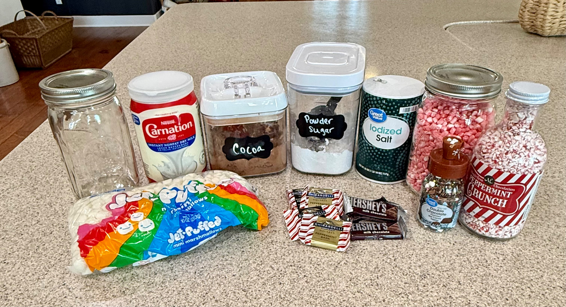 Hot cocoa ingredients and an empty quart jar with marshmallows, peppermint, chocolate, and sprinkles for toppings and homemade gifts.