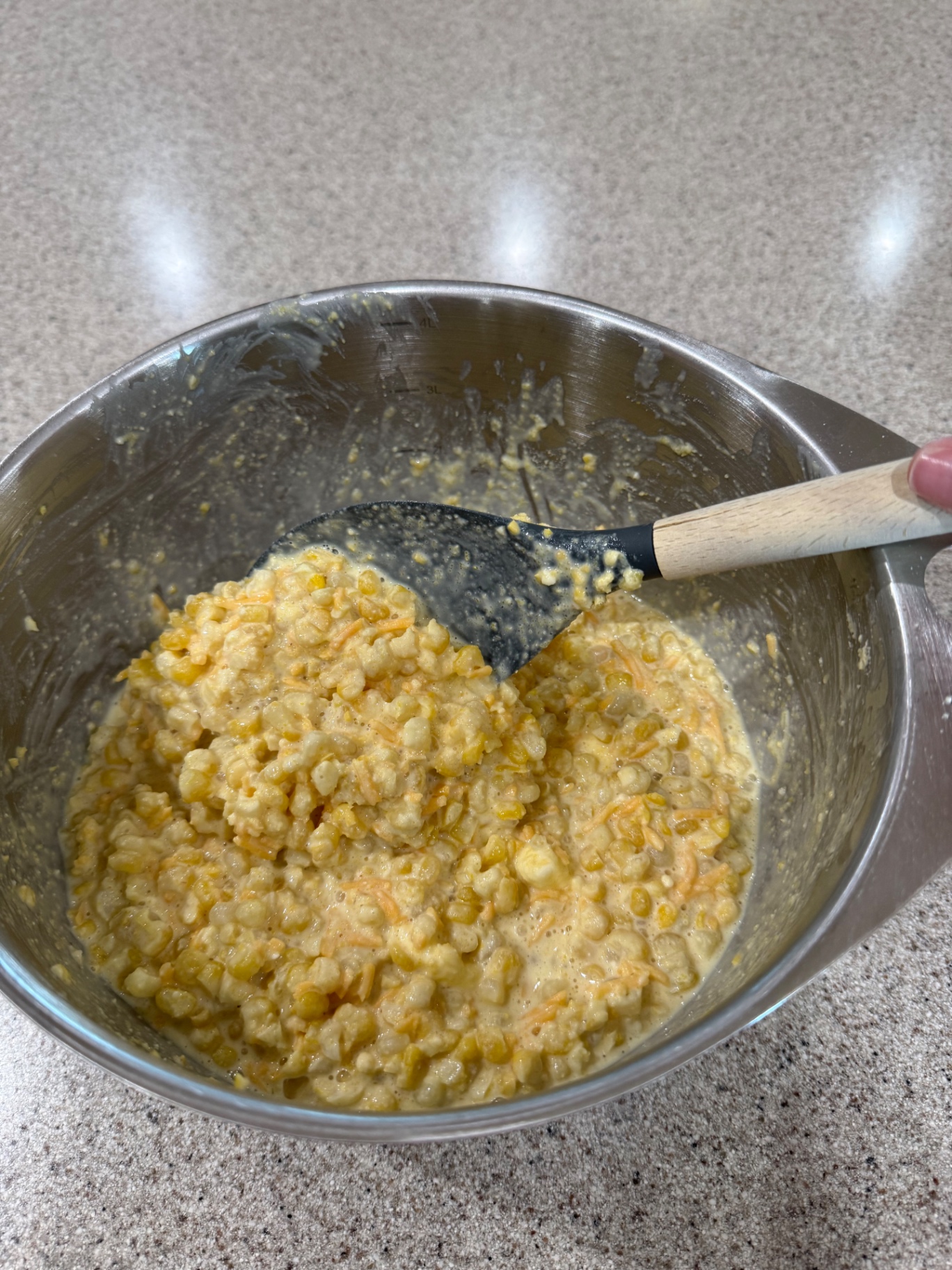 Fully mixed corn casserole batter with corn and cheddar in a metal mixing bowl.