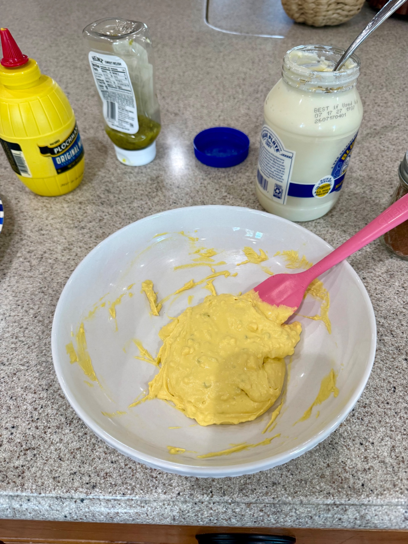 Creamy deviled egg filling in a white bowl with a pink spatula.