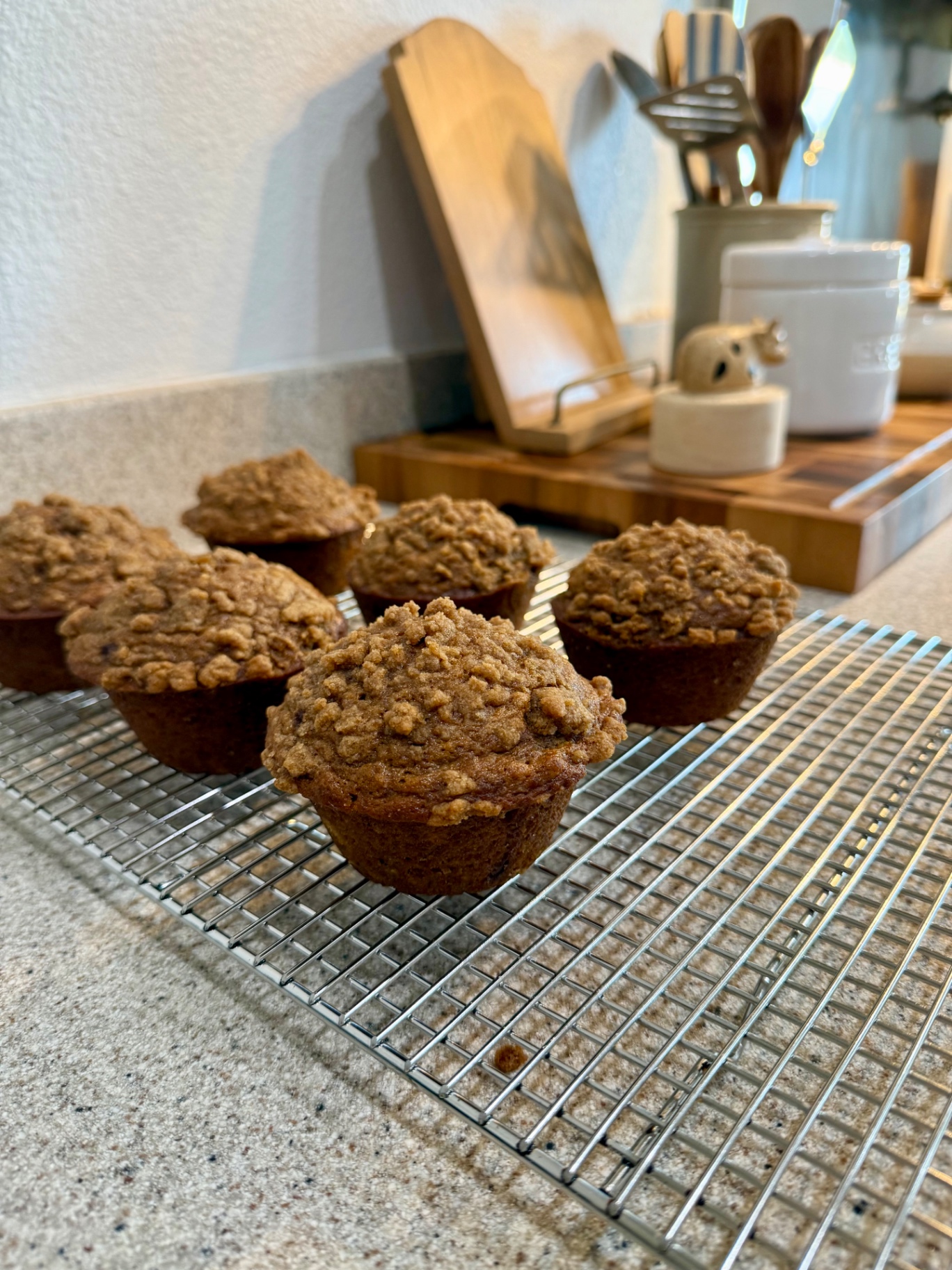 Banana pumpkin muffins topped with baked cinnamon crumble cooling on a wire rack.