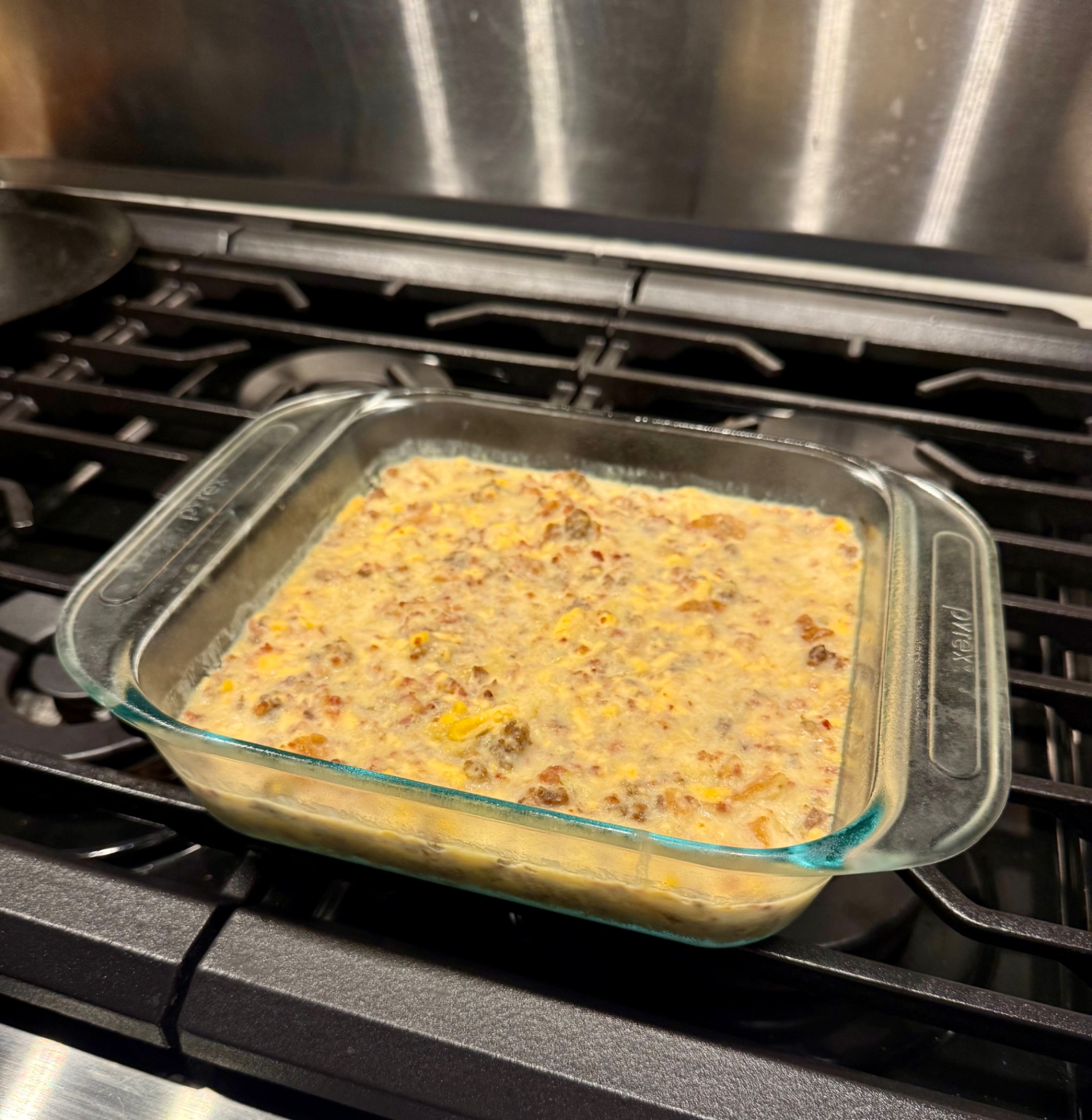 The soaked breakfast casserole in a glass baking dish on the stovetop the next morning before baking