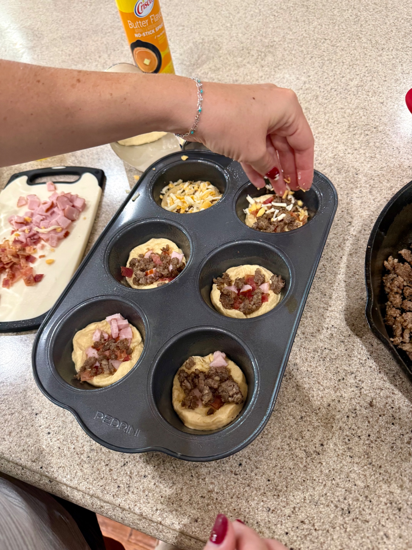 Breakfast meat and shredded cheese layered over biscuit dough in a jumbo muffin pan.