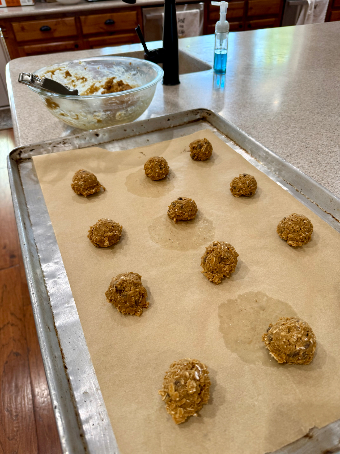 Scooped oatmeal cookie dough spaced apart on a parchment-lined baking sheet.