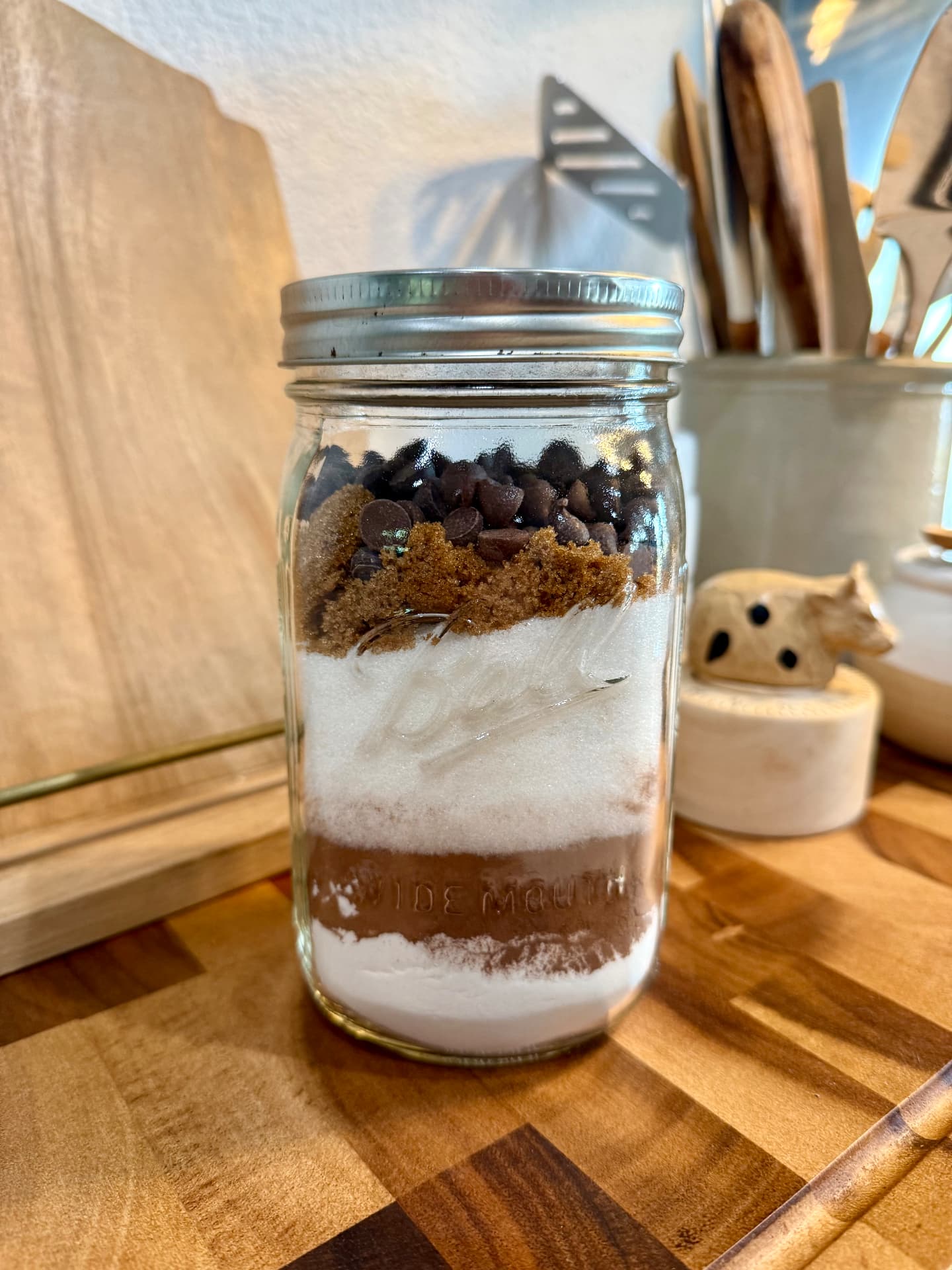 Layered brownie mix in a sealed wide-mouth quart mason jar: flour, cocoa, sugar, brown sugar, and chocolate chips.