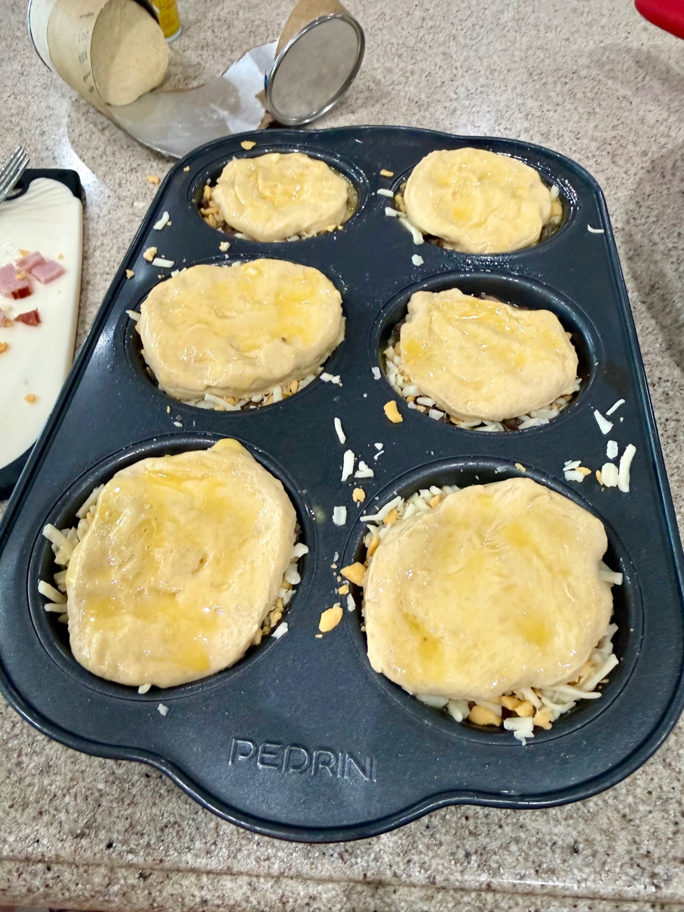 Loaded breakfast biscuits topped with biscuit dough before baking.