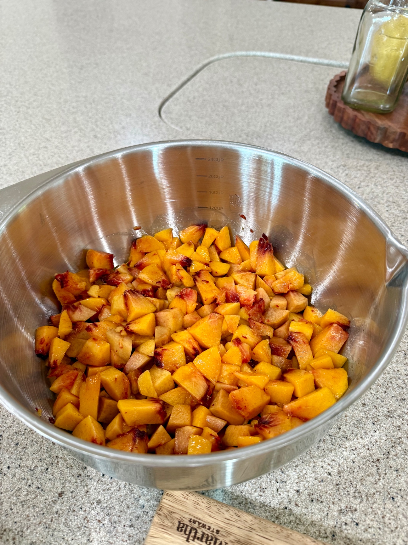 Eight measured cups of chopped and gently mashed yellow peaches in a large stainless steel bowl