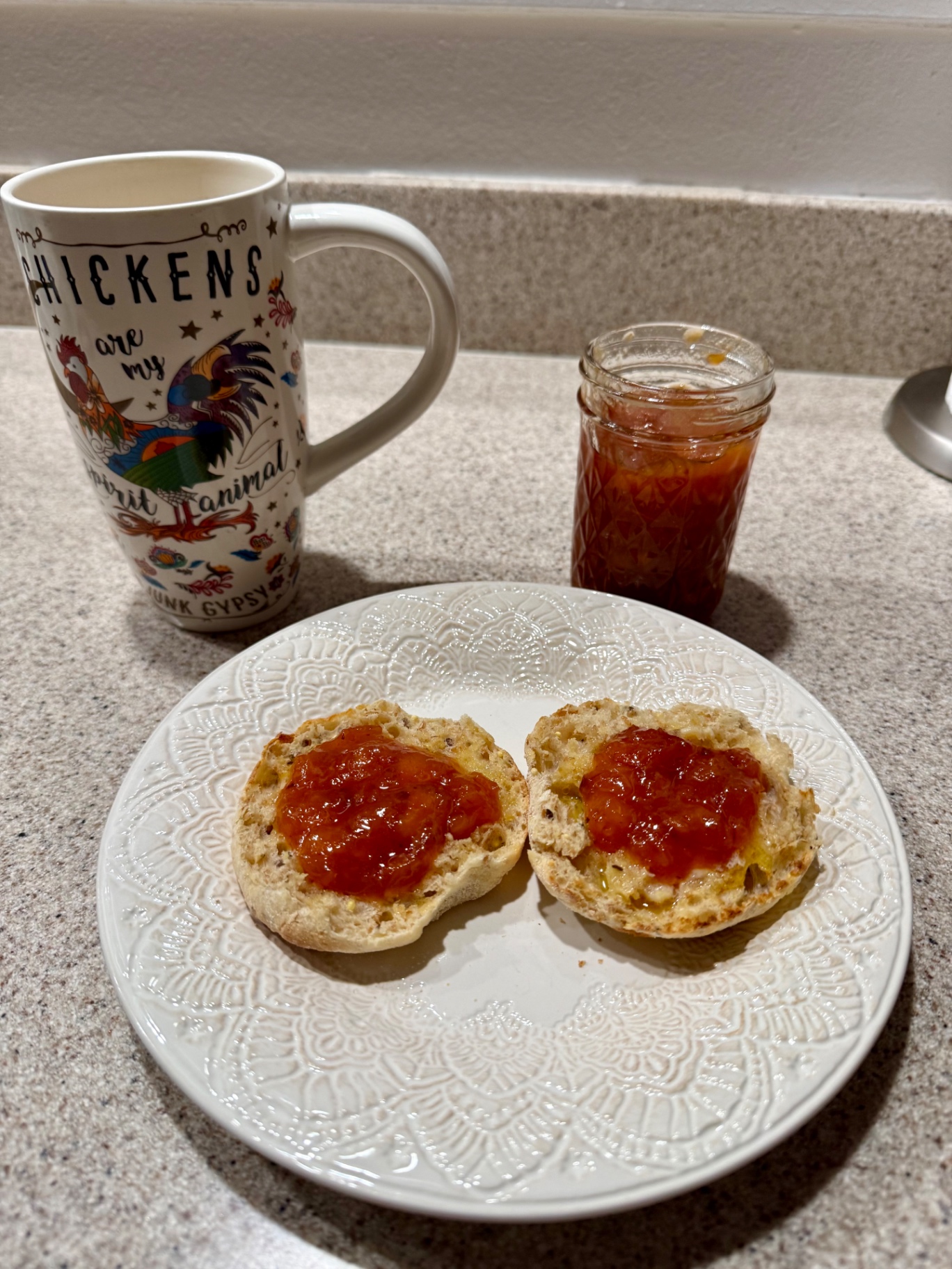 A warm split biscuit topped with homemade peach topping on a decorative plate beside a mug