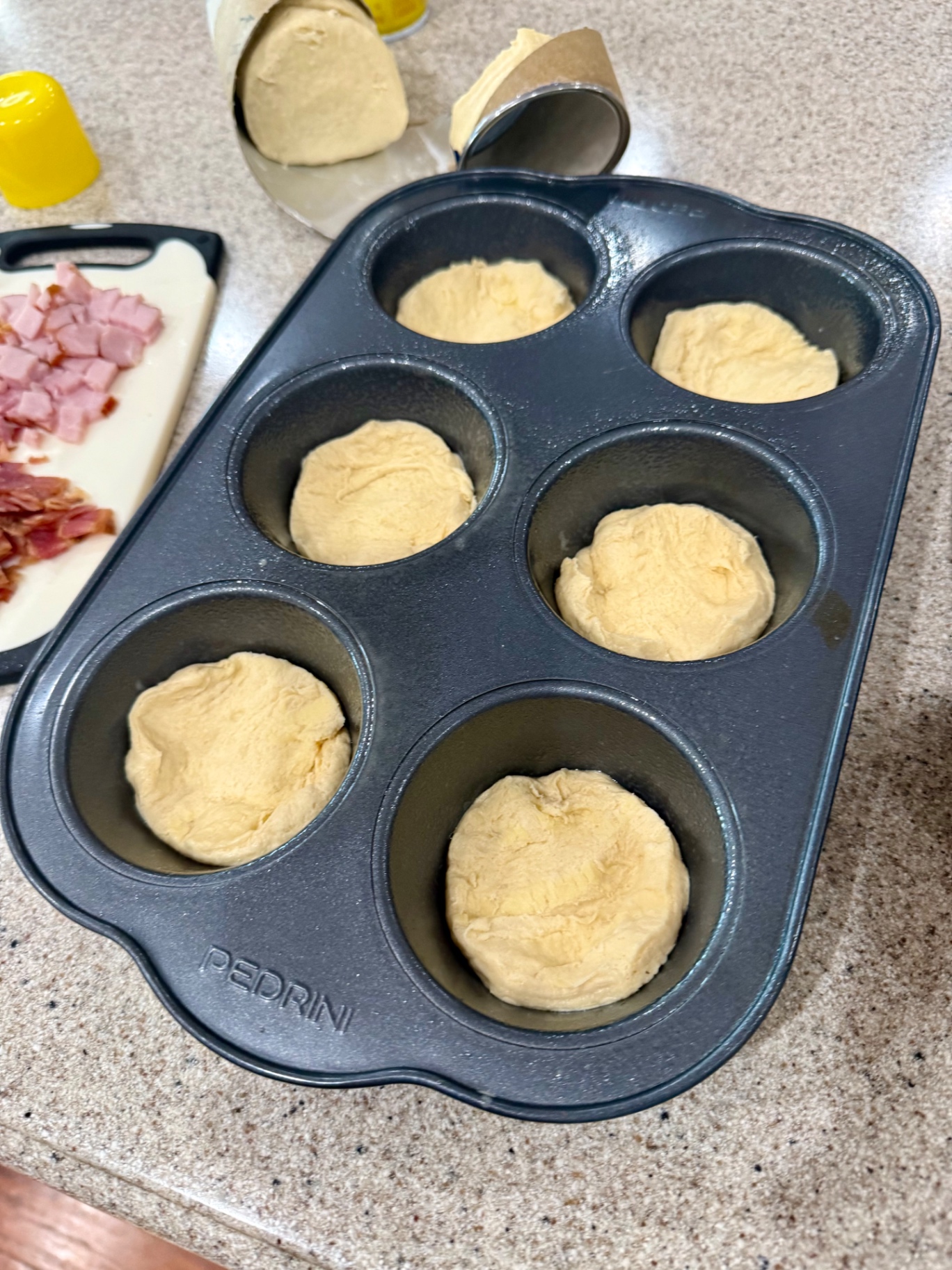 Biscuit halves pressed into a greased jumbo muffin pan.