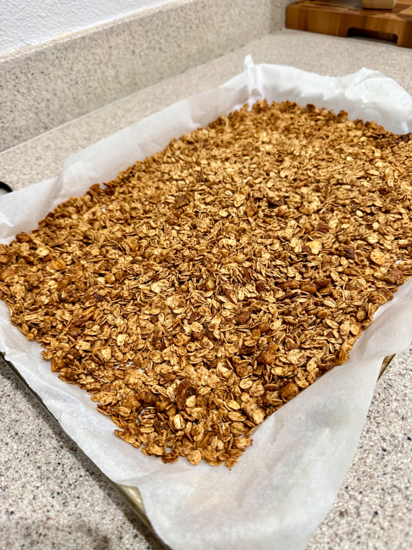 Baked honey cinnamon walnut granola spread on a parchment-lined baking sheet.