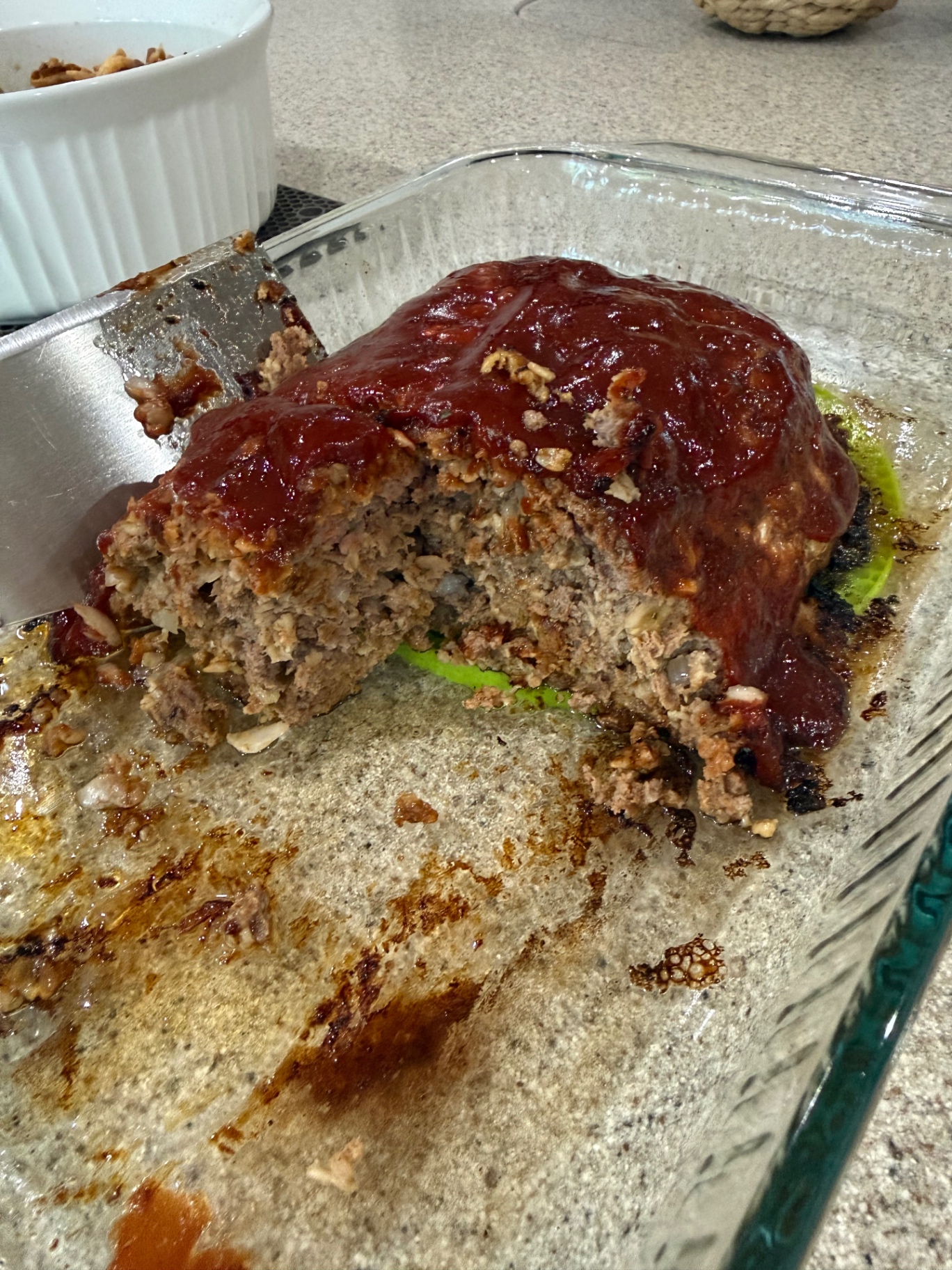 Cut-open meatloaf in the baking dish showing the tender interior with oats and onion.