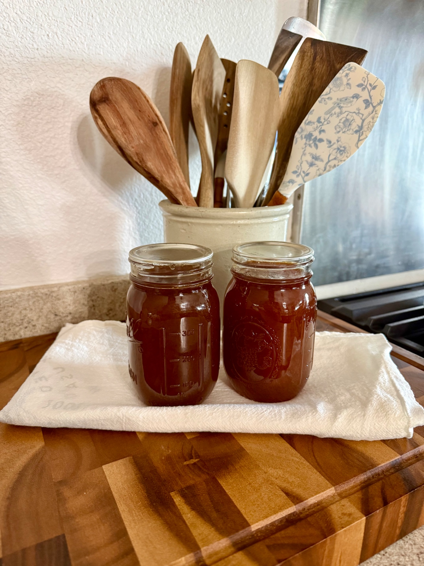 Jars of dark homemade plum jam cooling on the counter