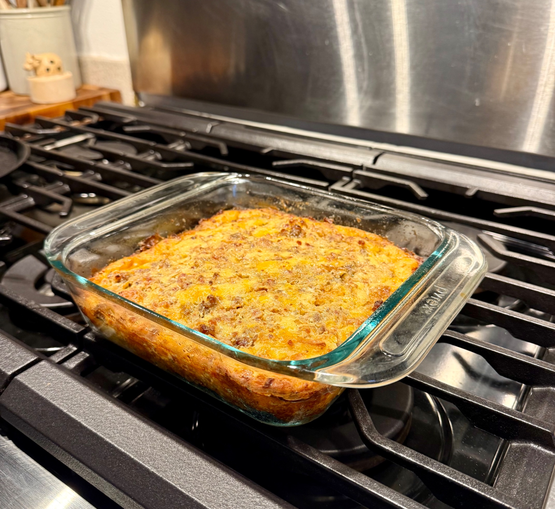 A glass baking dish of golden baked sausage breakfast casserole resting on the stovetop