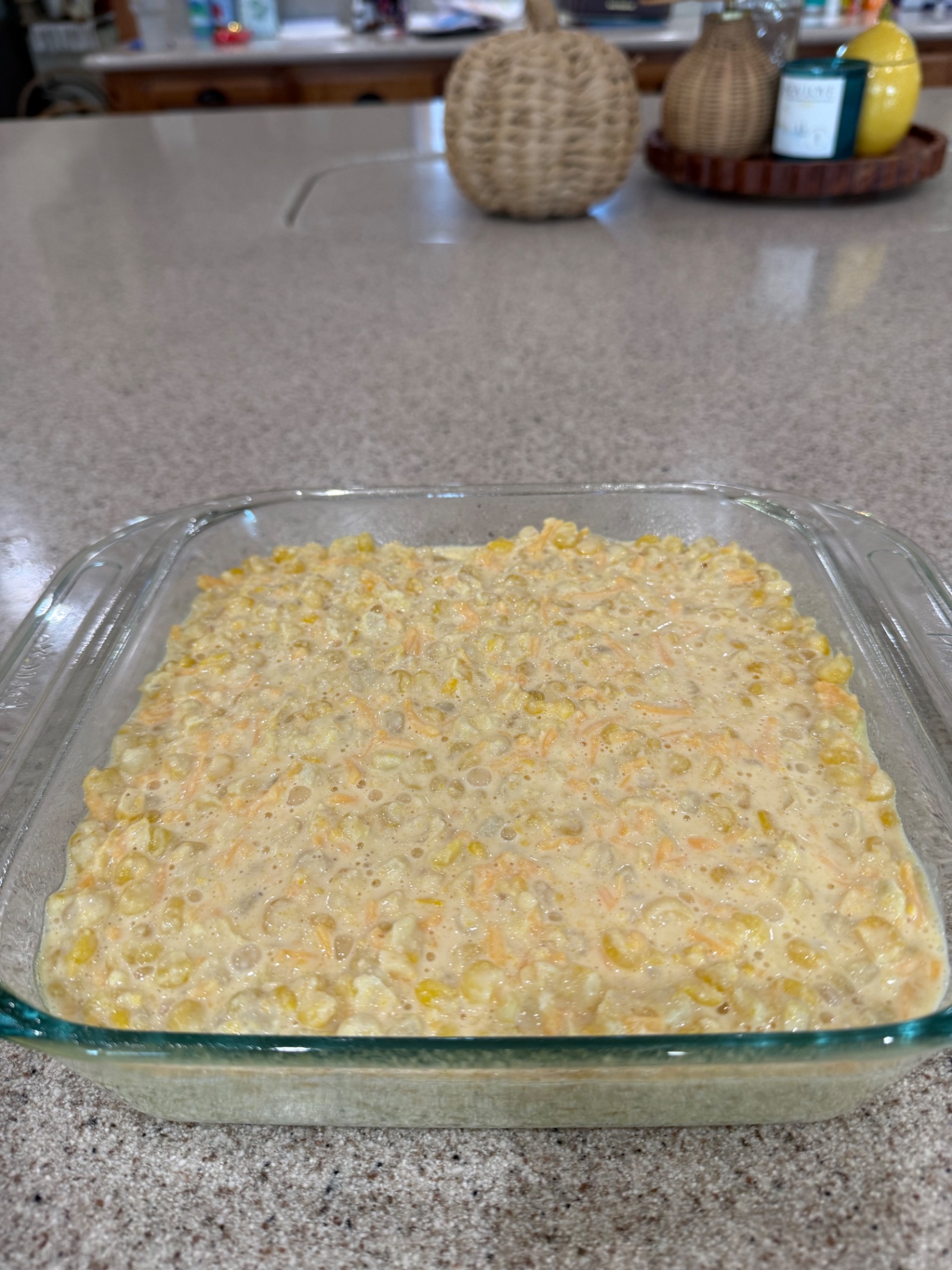 Unbaked corn casserole mixture spread evenly in an 8x8-inch glass baking dish.
