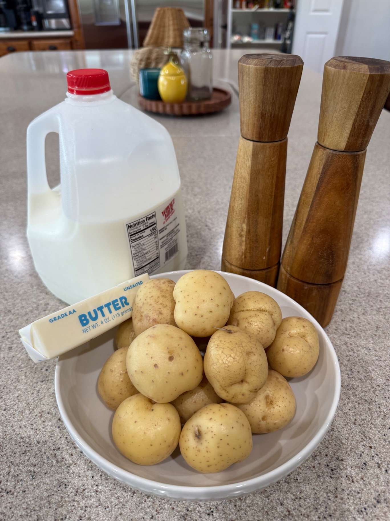 Yukon Gold potatoes, milk, butter, and salt and pepper mills arranged on the kitchen counter.