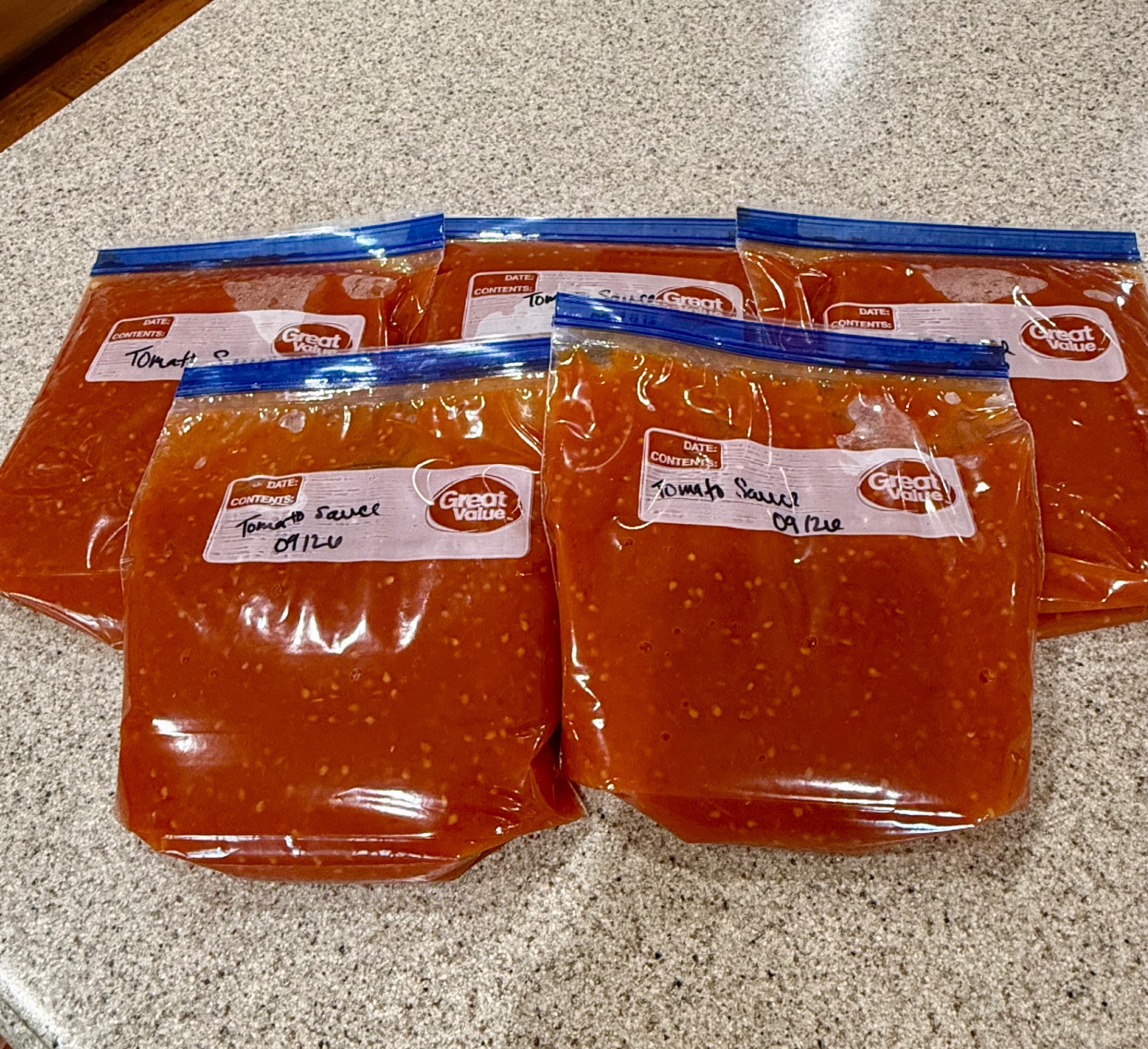 Five quart freezer bags filled with homemade tomato sauce made from frozen garden tomatoes.