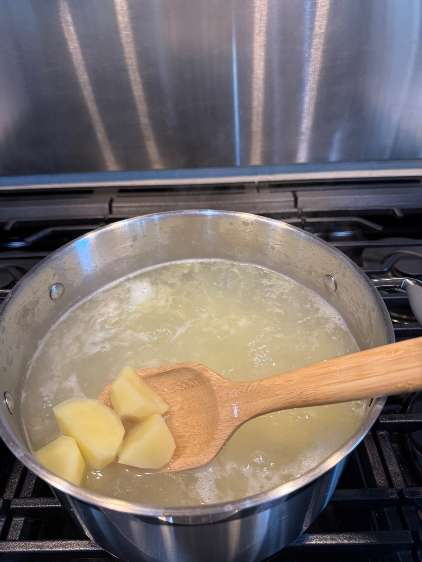 Yukon Gold potato chunks boiling in a pot on the stovetop.