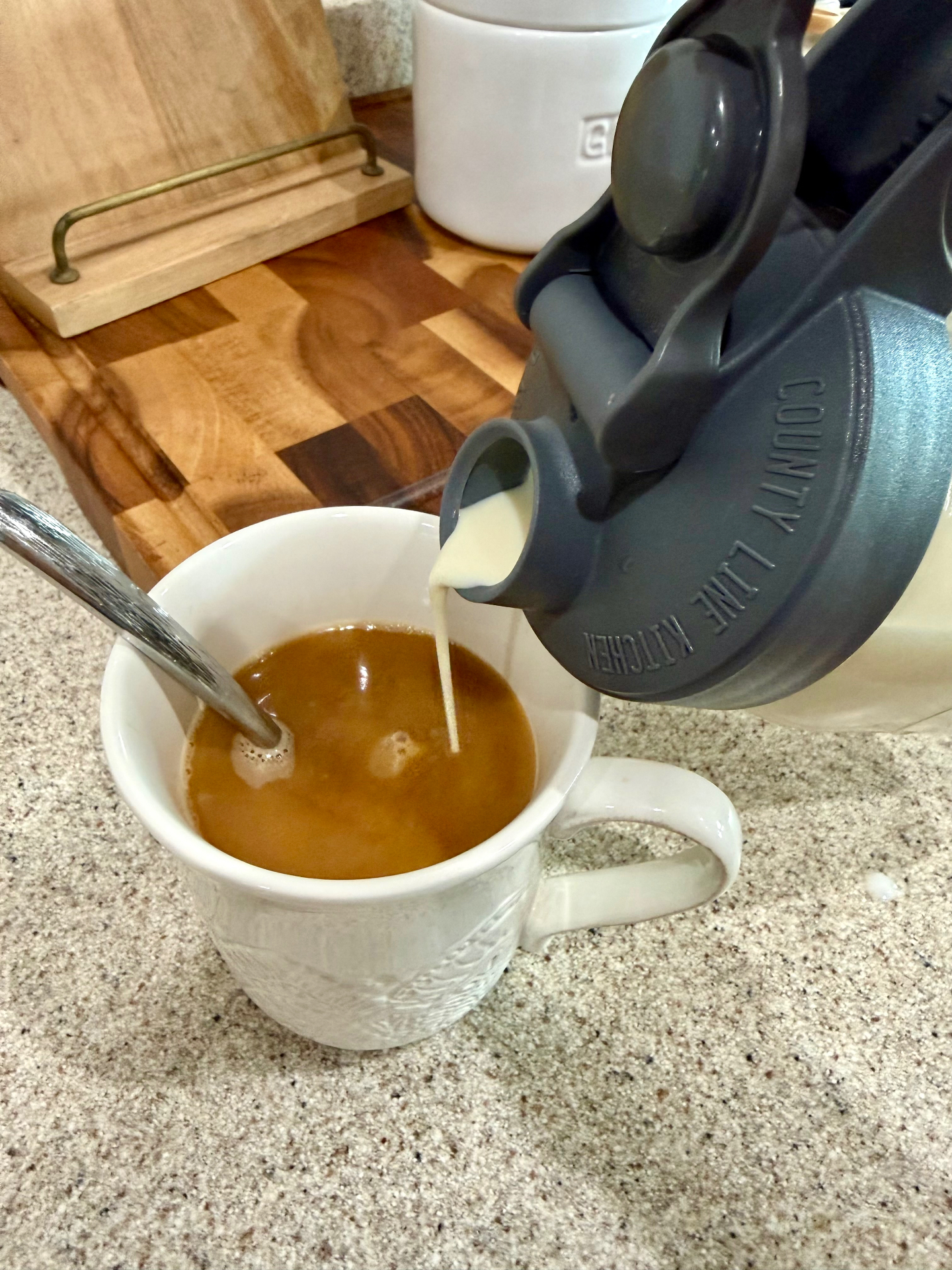 Homemade creamer pouring from a mason jar pour lid into a mug of coffee.