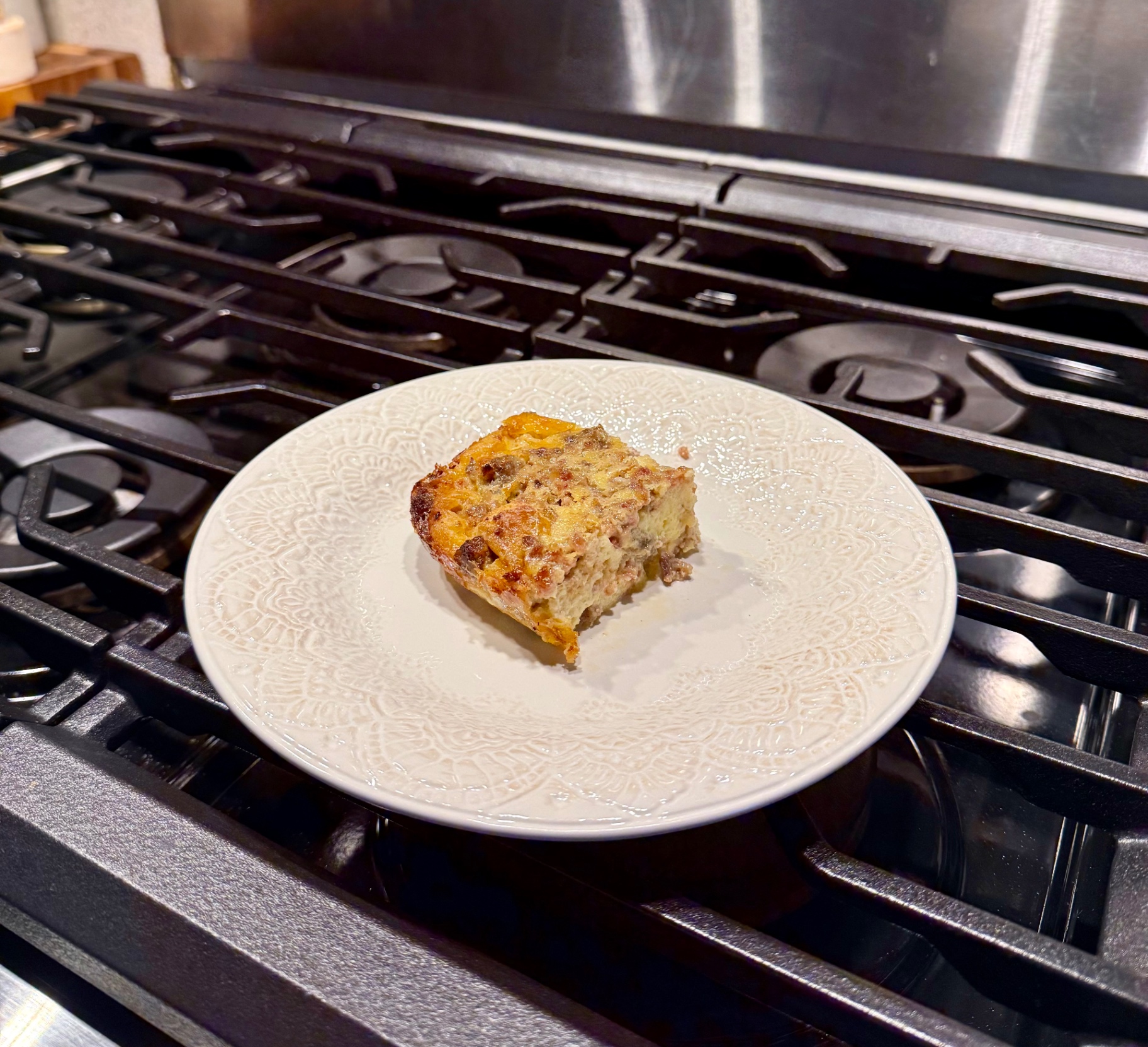 A square slice of baked sausage breakfast casserole served on a white plate