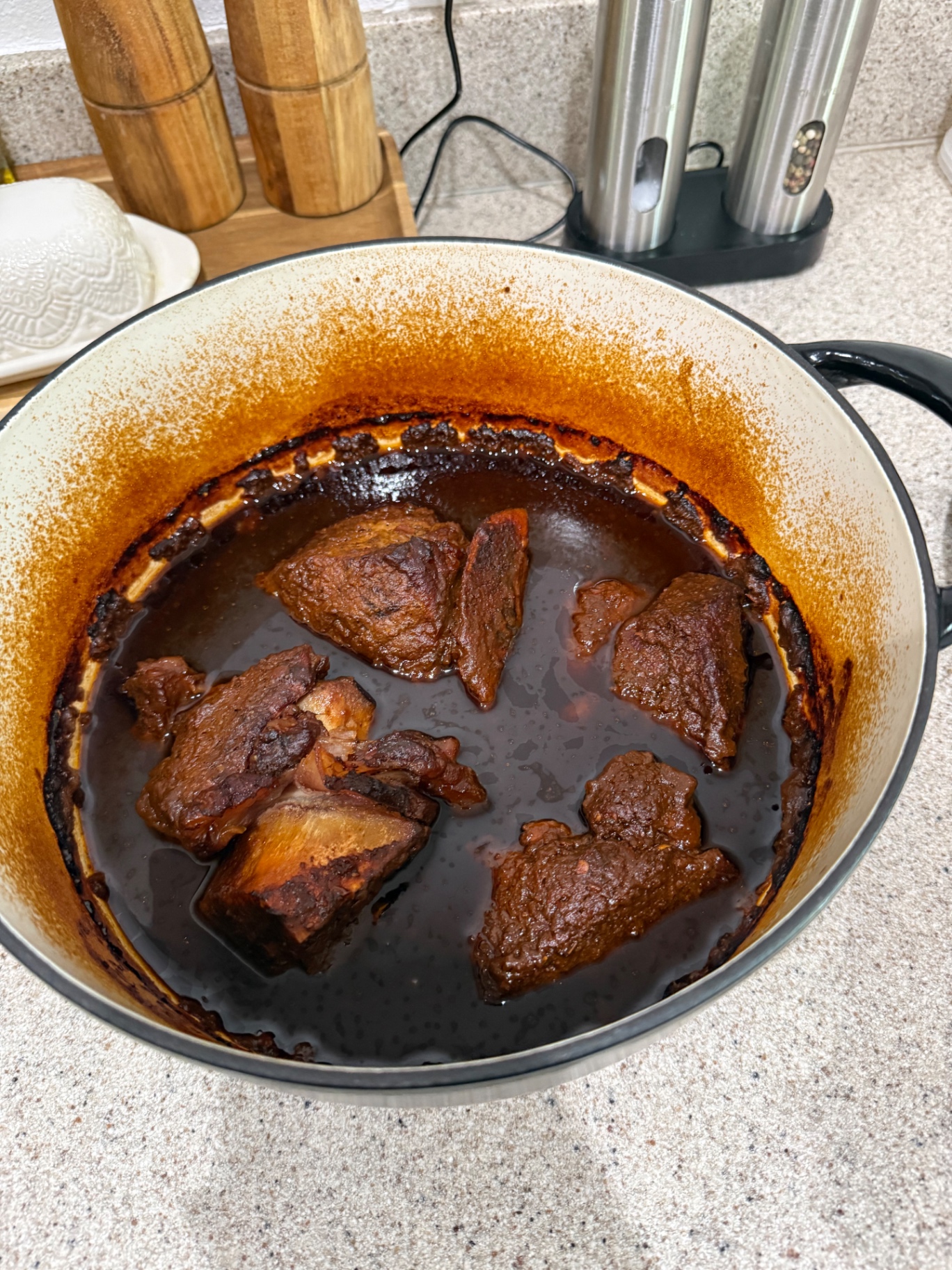 Birria beef braising in a white enameled Dutch oven