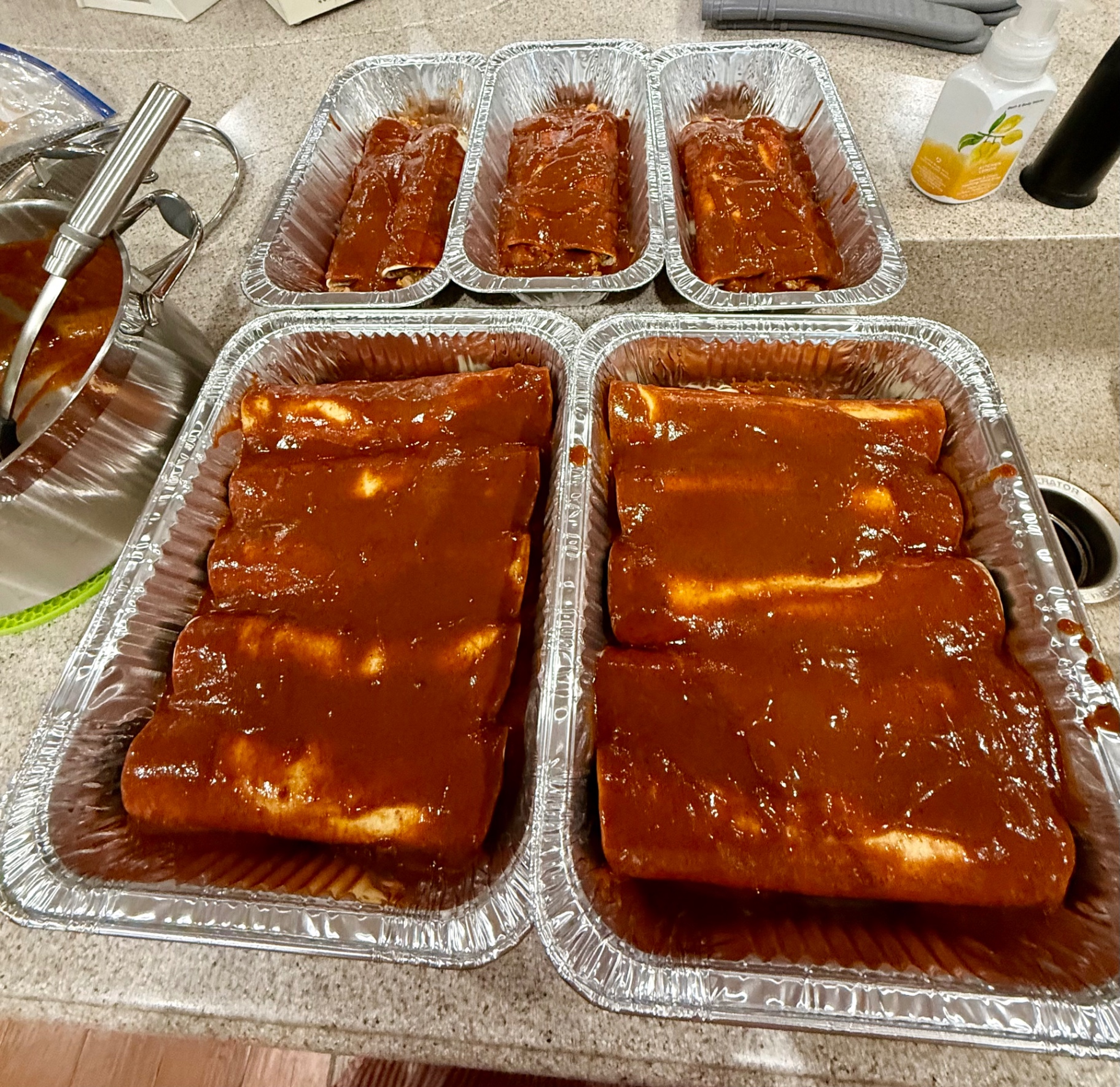 Foil pans of rolled beef enchiladas covered in homemade red sauce
