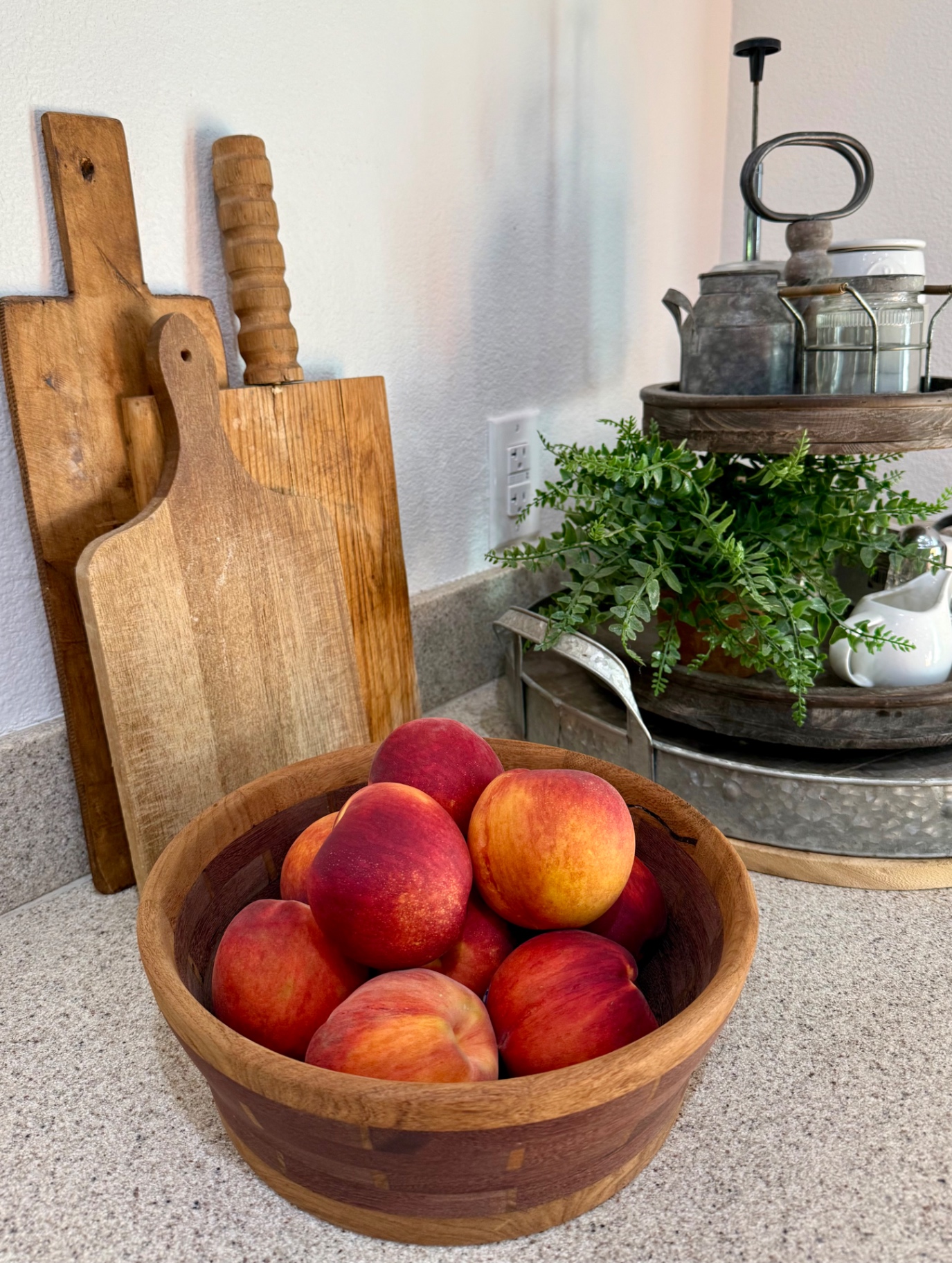 Fresh whole yellow-flesh peaches piled in a wooden bowl on the kitchen counter