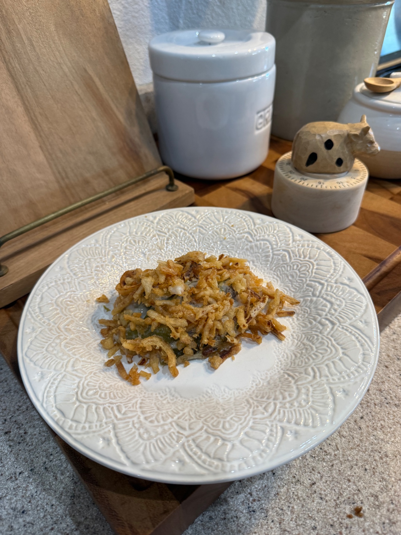 A plated serving of green bean casserole on a white patterned plate in the Pasture Threads kitchen.