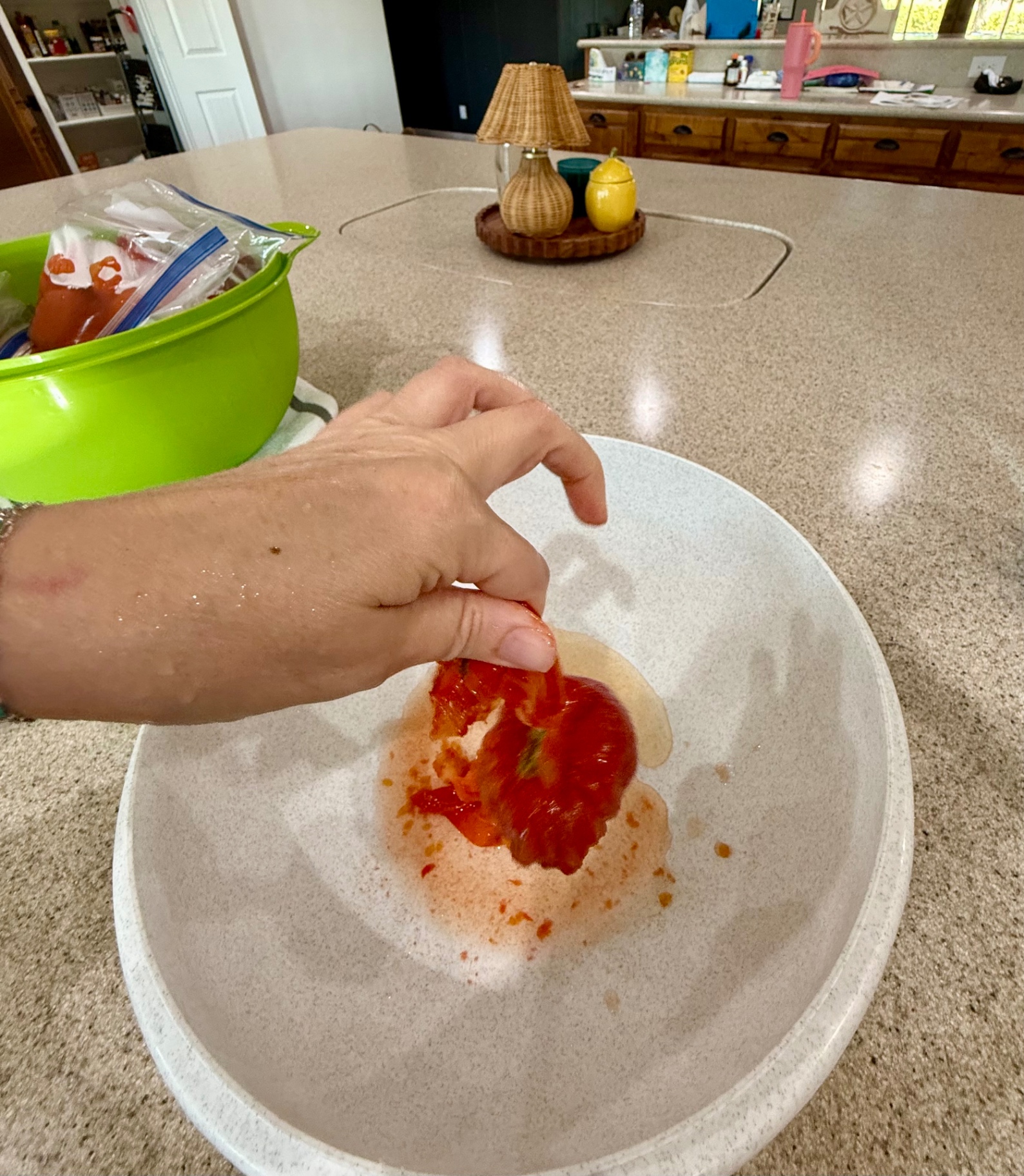 Peeling the loose skin from a thawed garden tomato over a bowl used to collect the skins and cores.