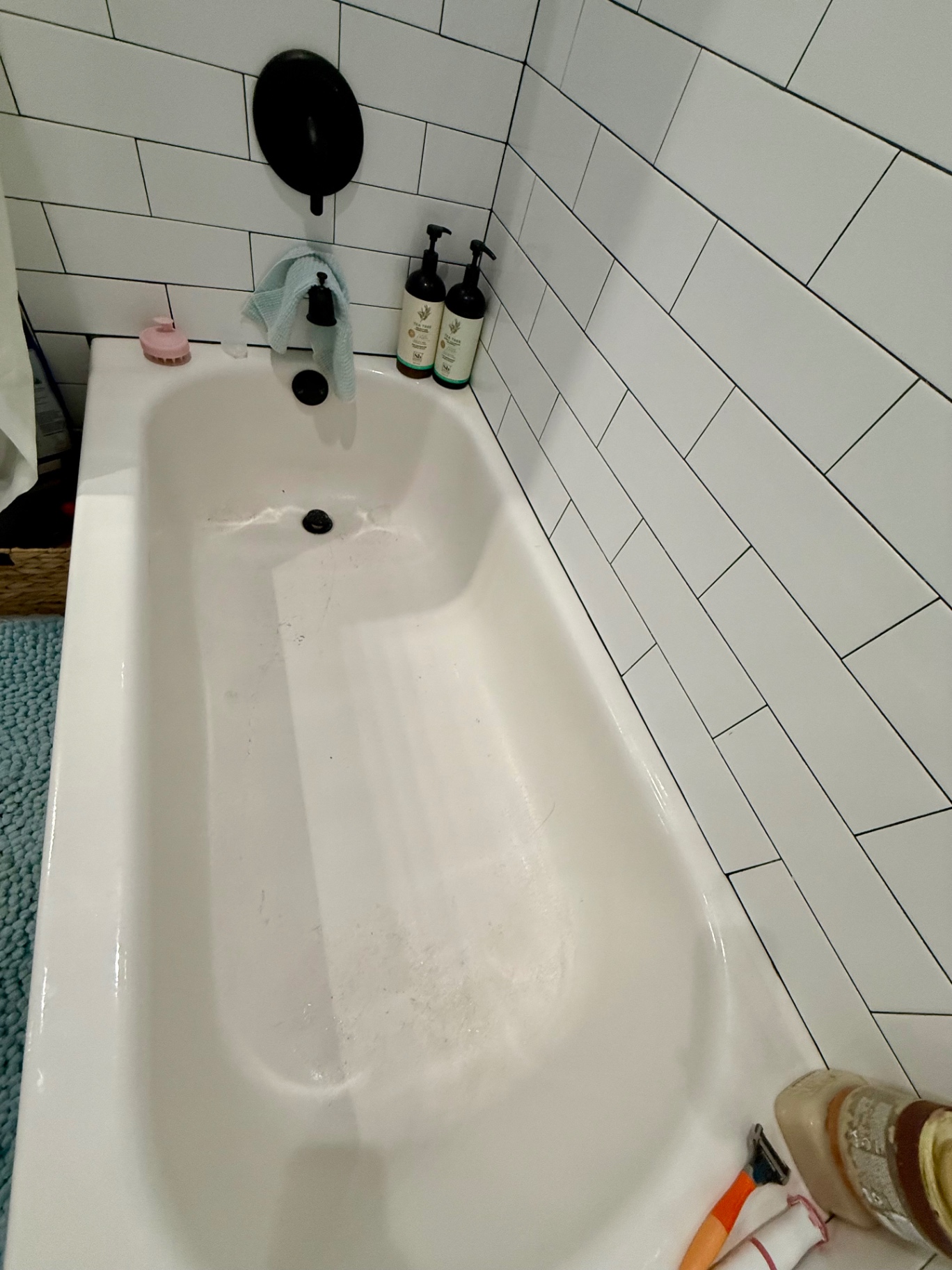 White bathtub mid-clean with subway tile surround