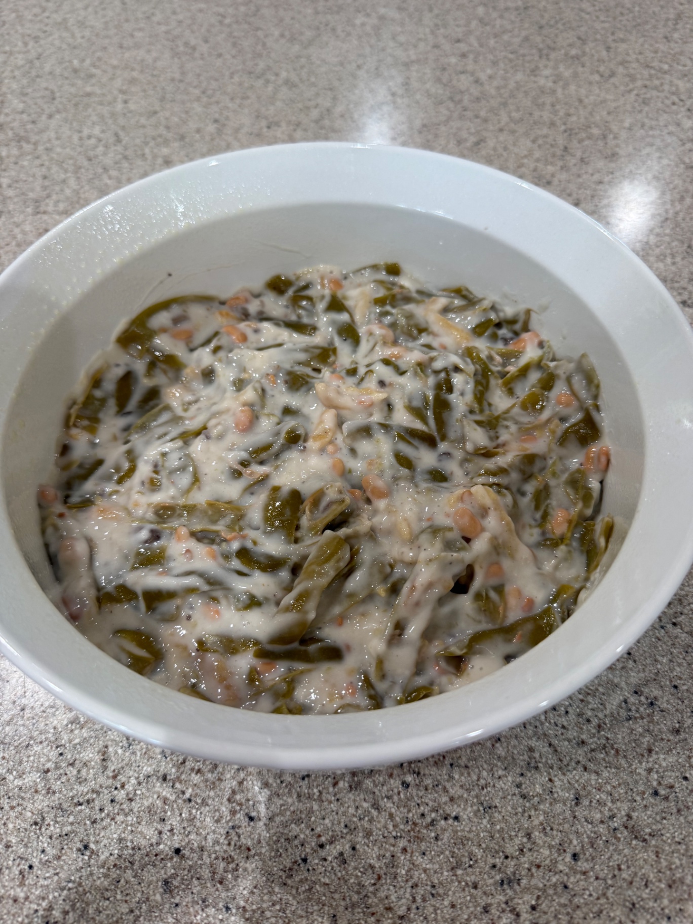 Mixed green bean casserole spread in a white baking dish before baking.
