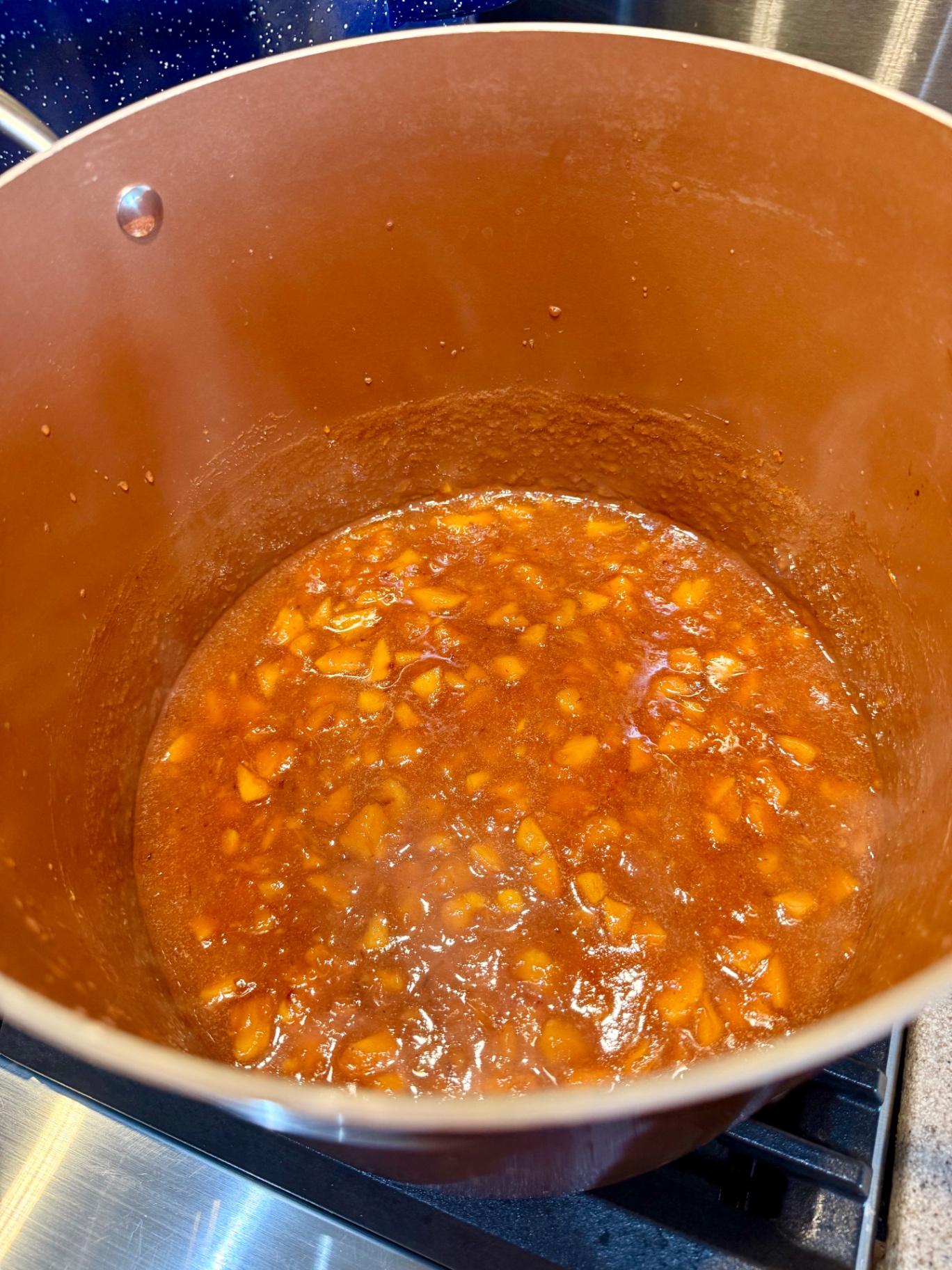 Homemade peach topping bubbling and thickening in a large pot on the stove