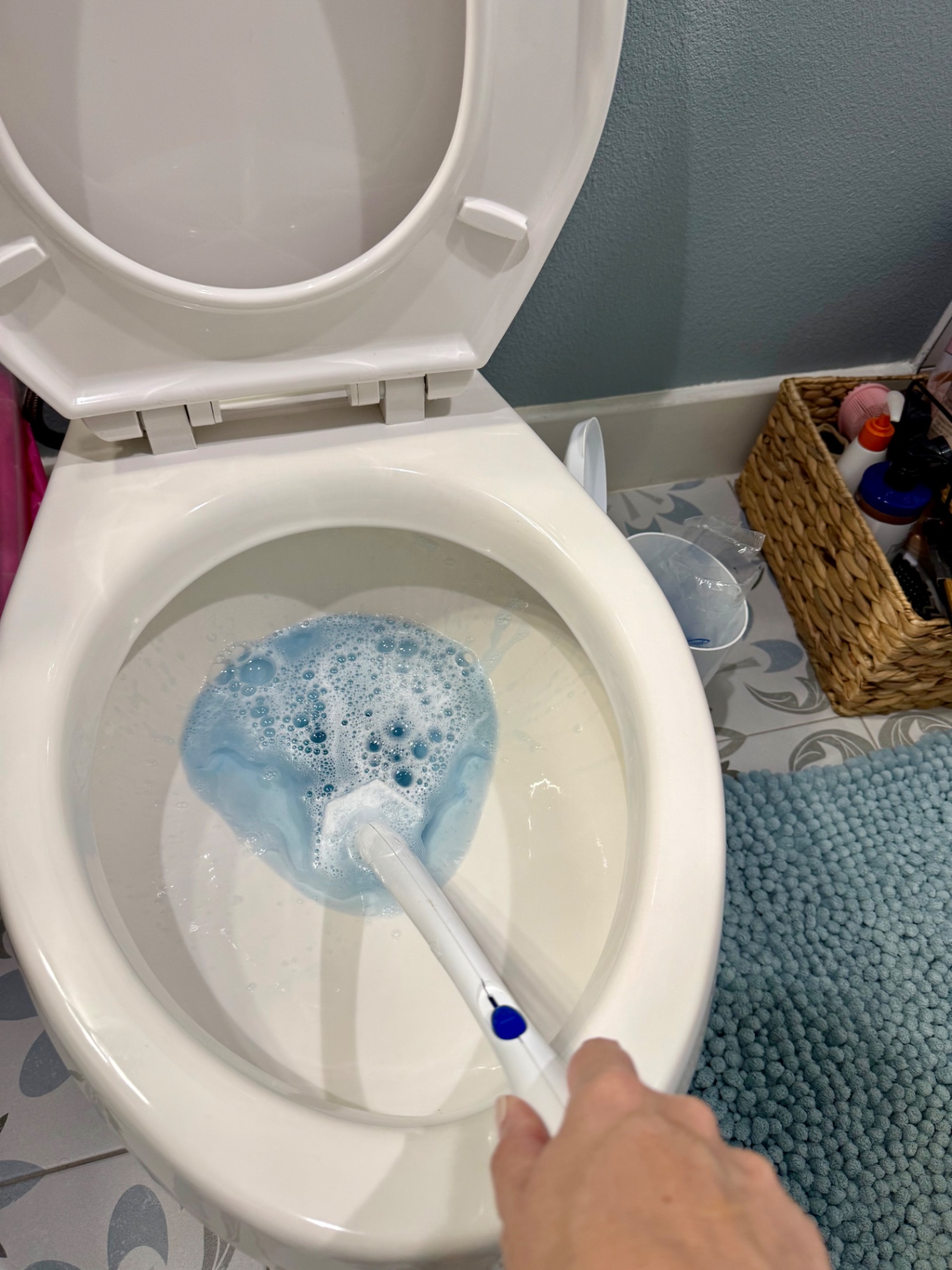 Cleaning the inside of a toilet bowl with a disposable-head toilet wand
