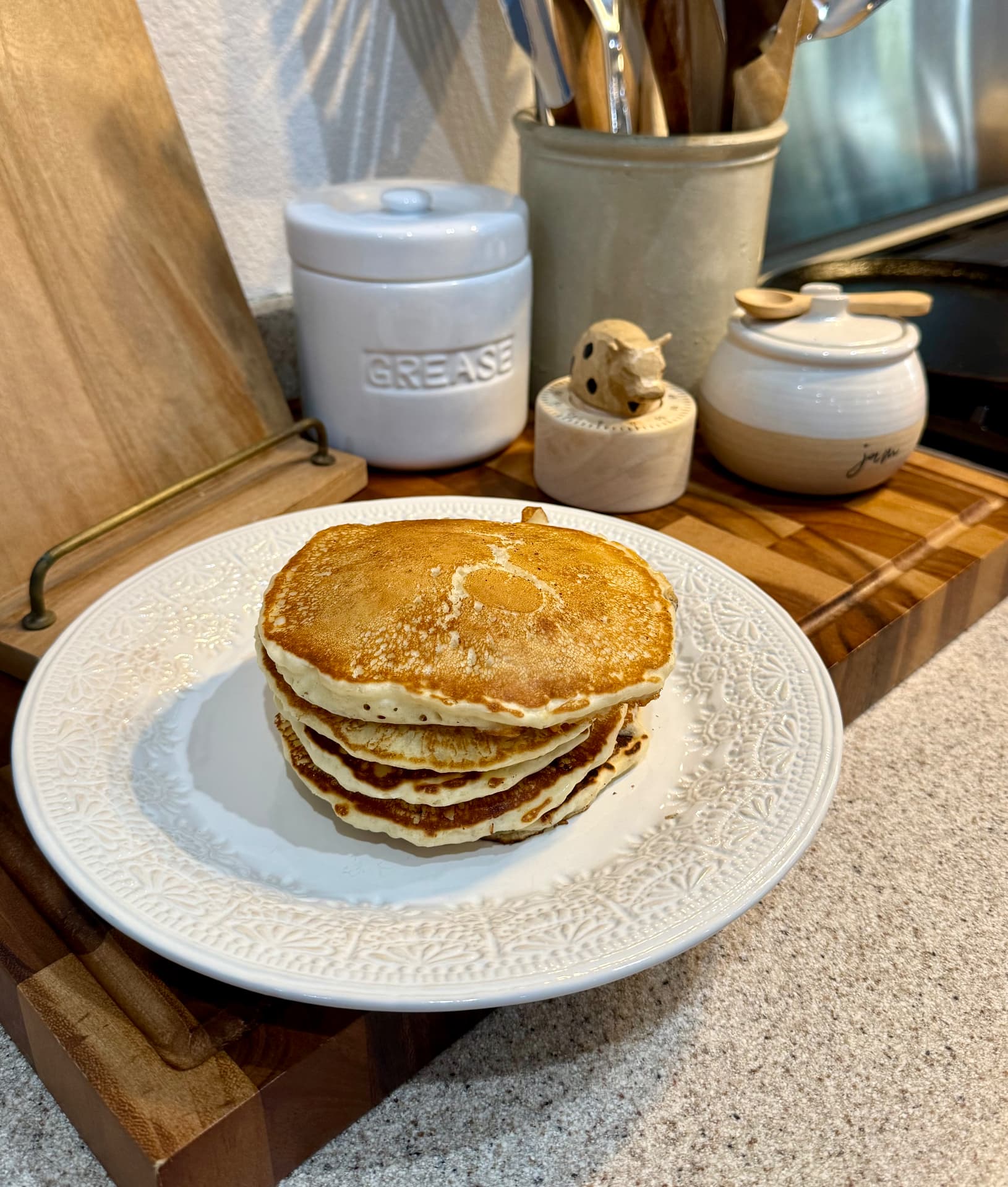 A stack of golden fluffy pancakes on a white patterned plate.