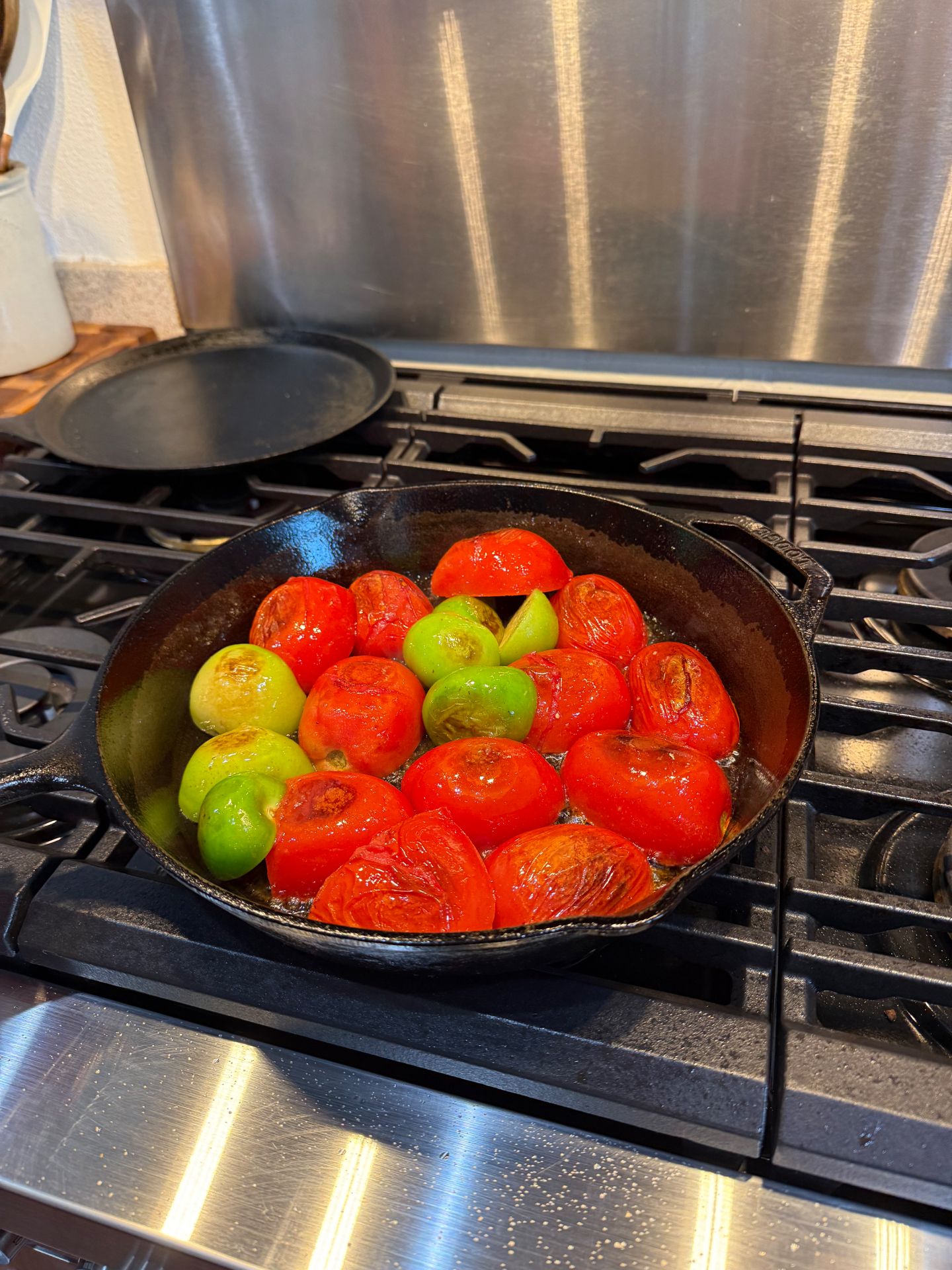 Red and green tomatoes cooking in a Lodge cast iron skillet on the stovetop